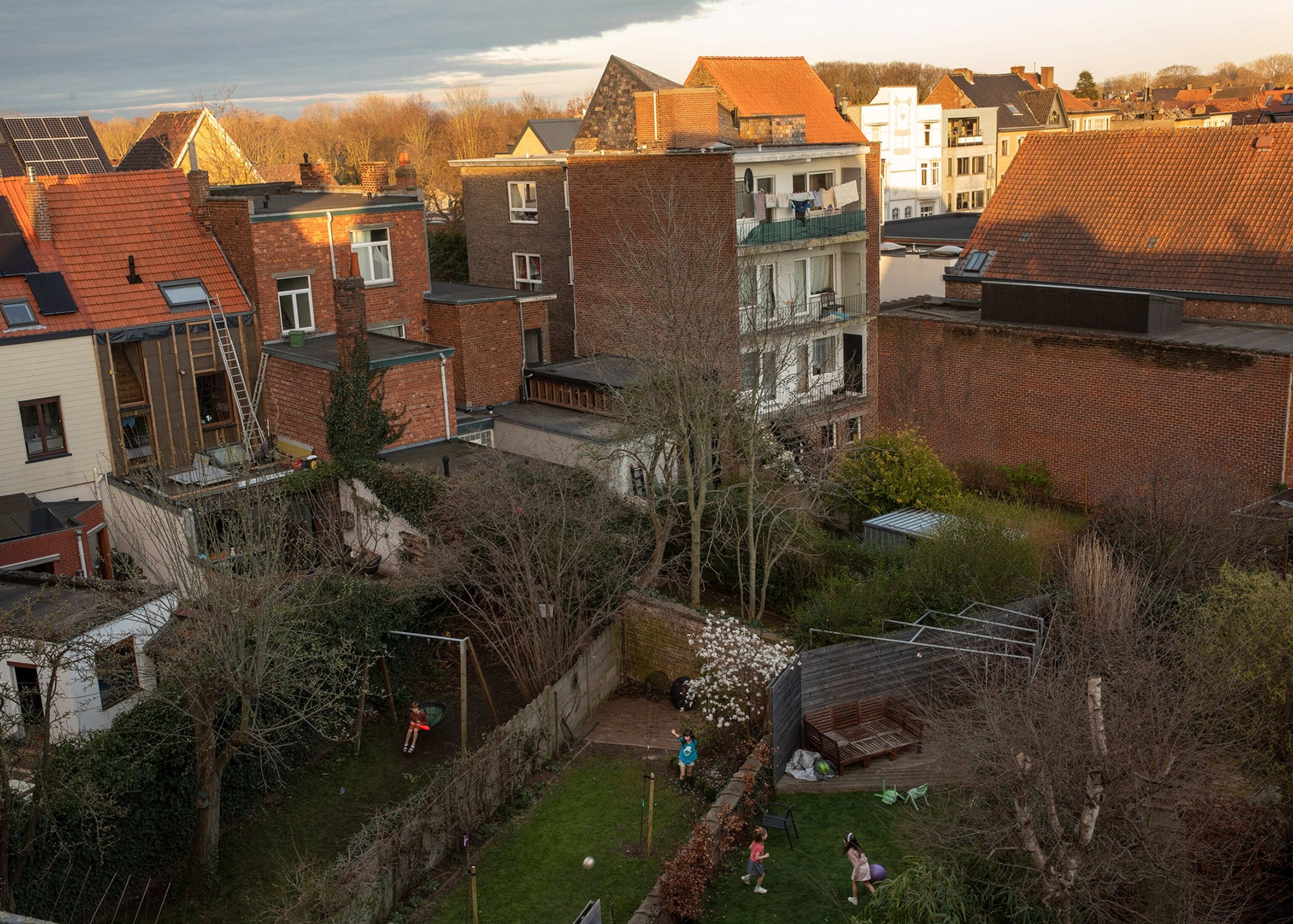 children playing in backyards separated by fences in Belgium