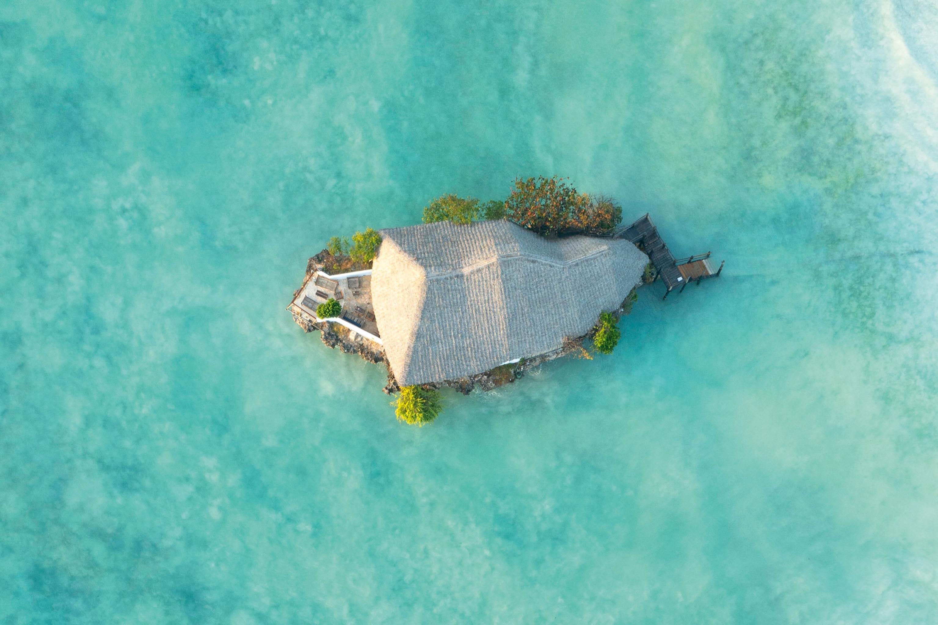 aerial shot of very small island surrounded by clear blue waters