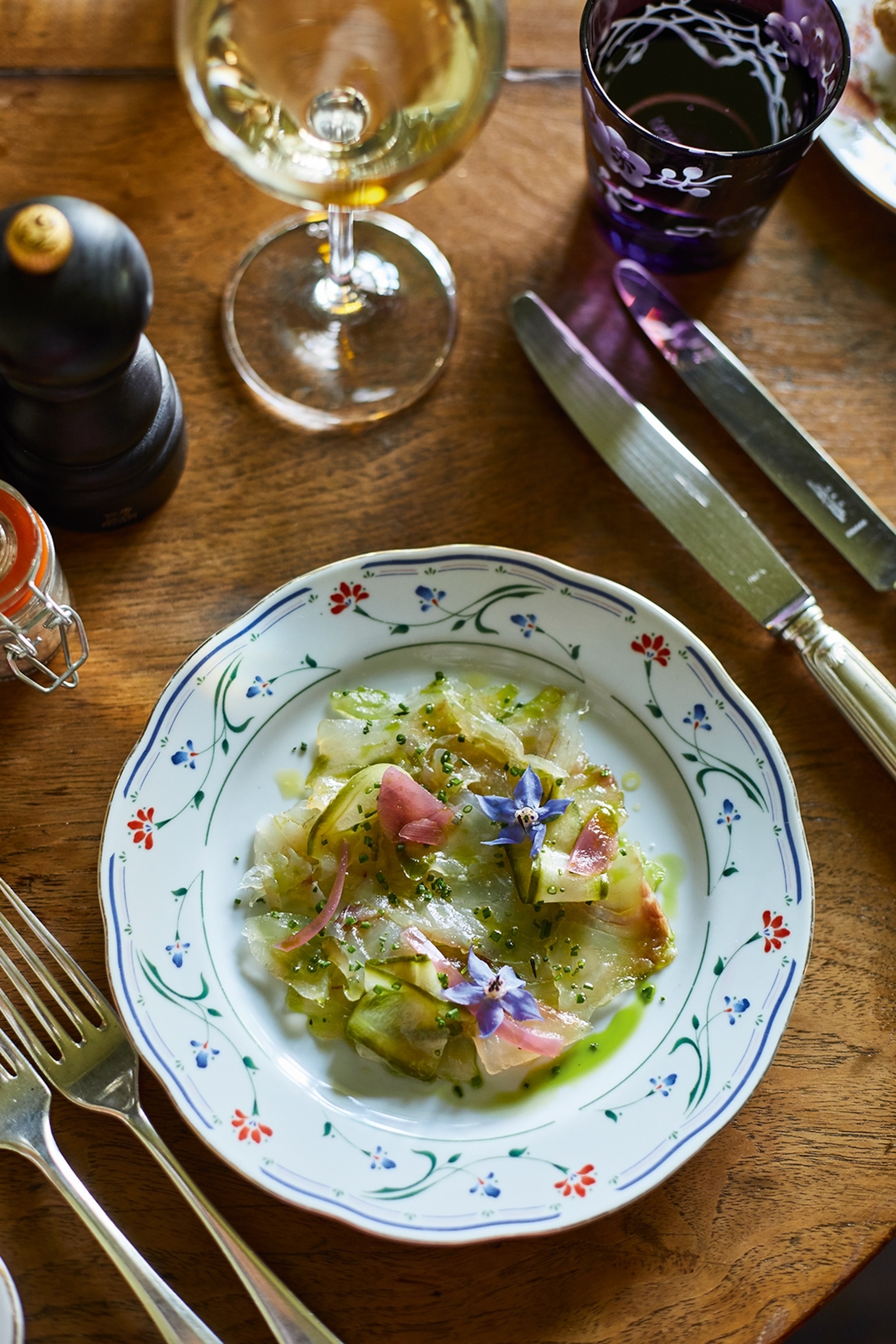 A chic formally decked table with colourful glassware and a pickled vegetable salad on floral china.