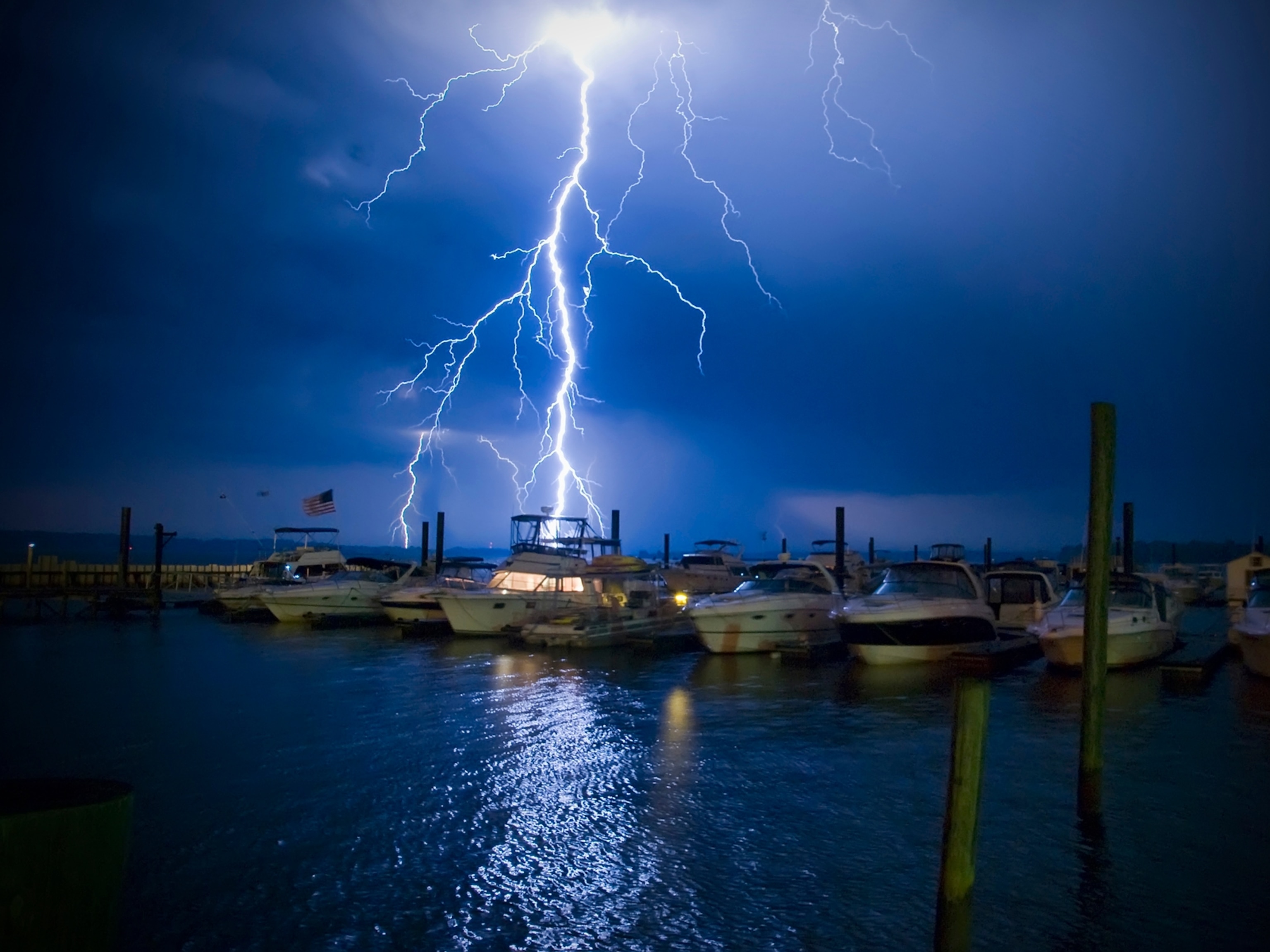 Lightning strikes behind a boat with lights on
