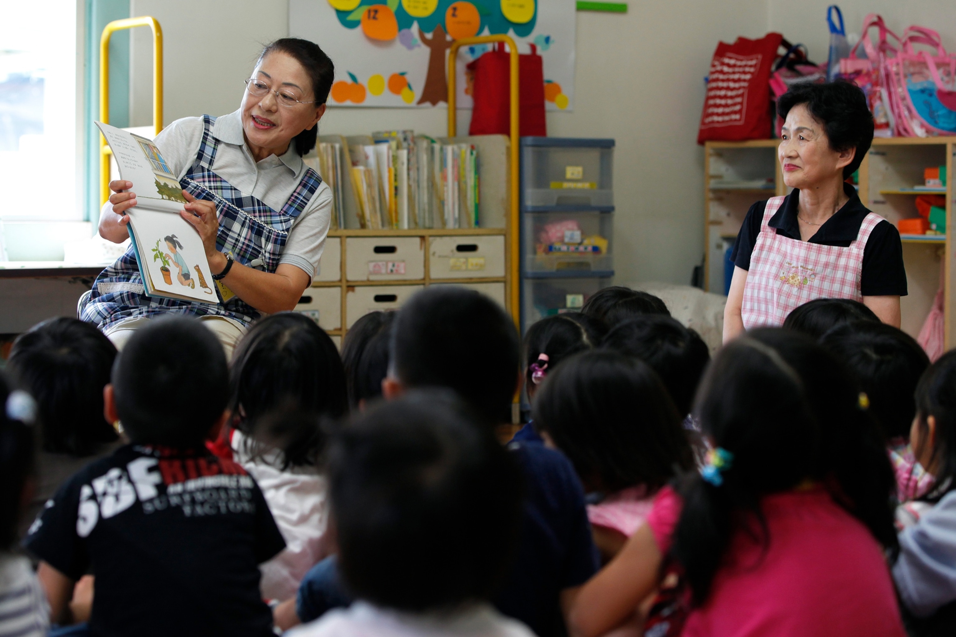 Photo of older woman reading to room full of children