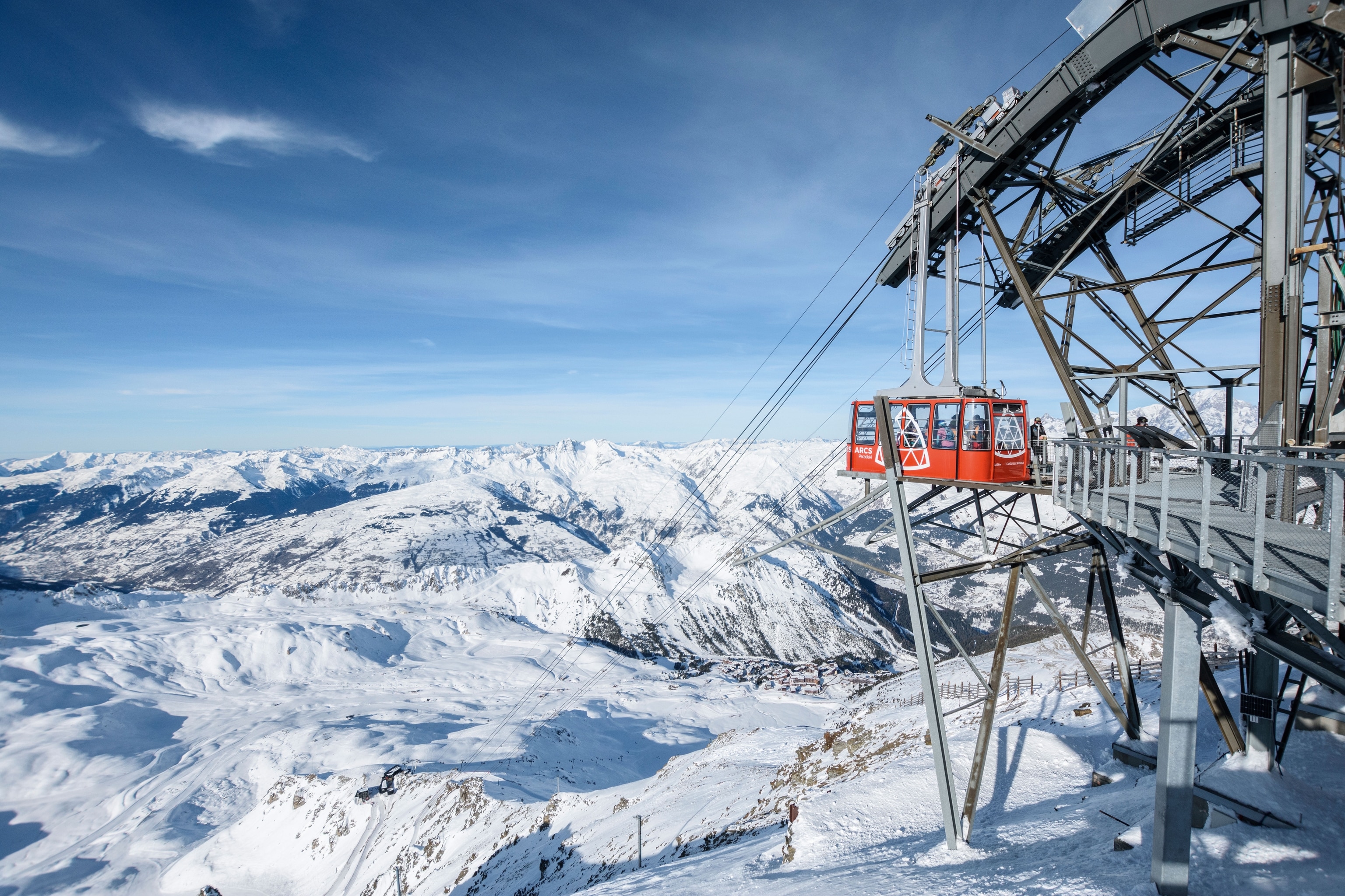 red cable cart descending with snow slopes in the background