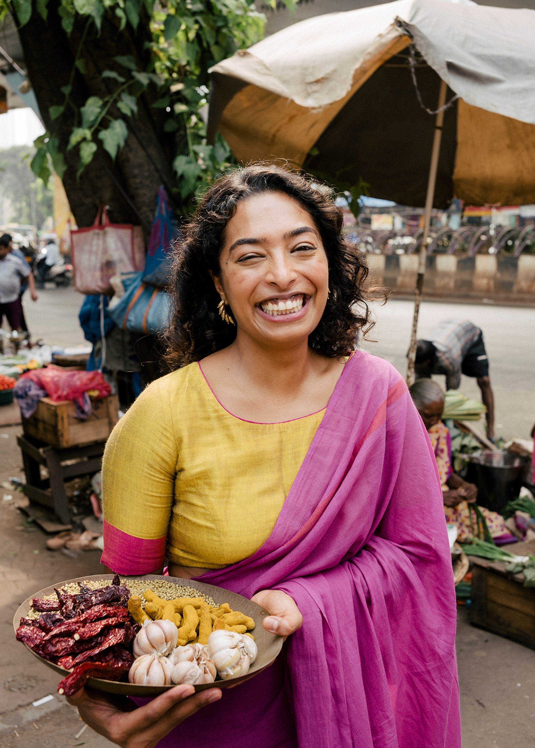 A woman smiles for a picture as she holds a plate of garlic, pepper, and other seasonings.