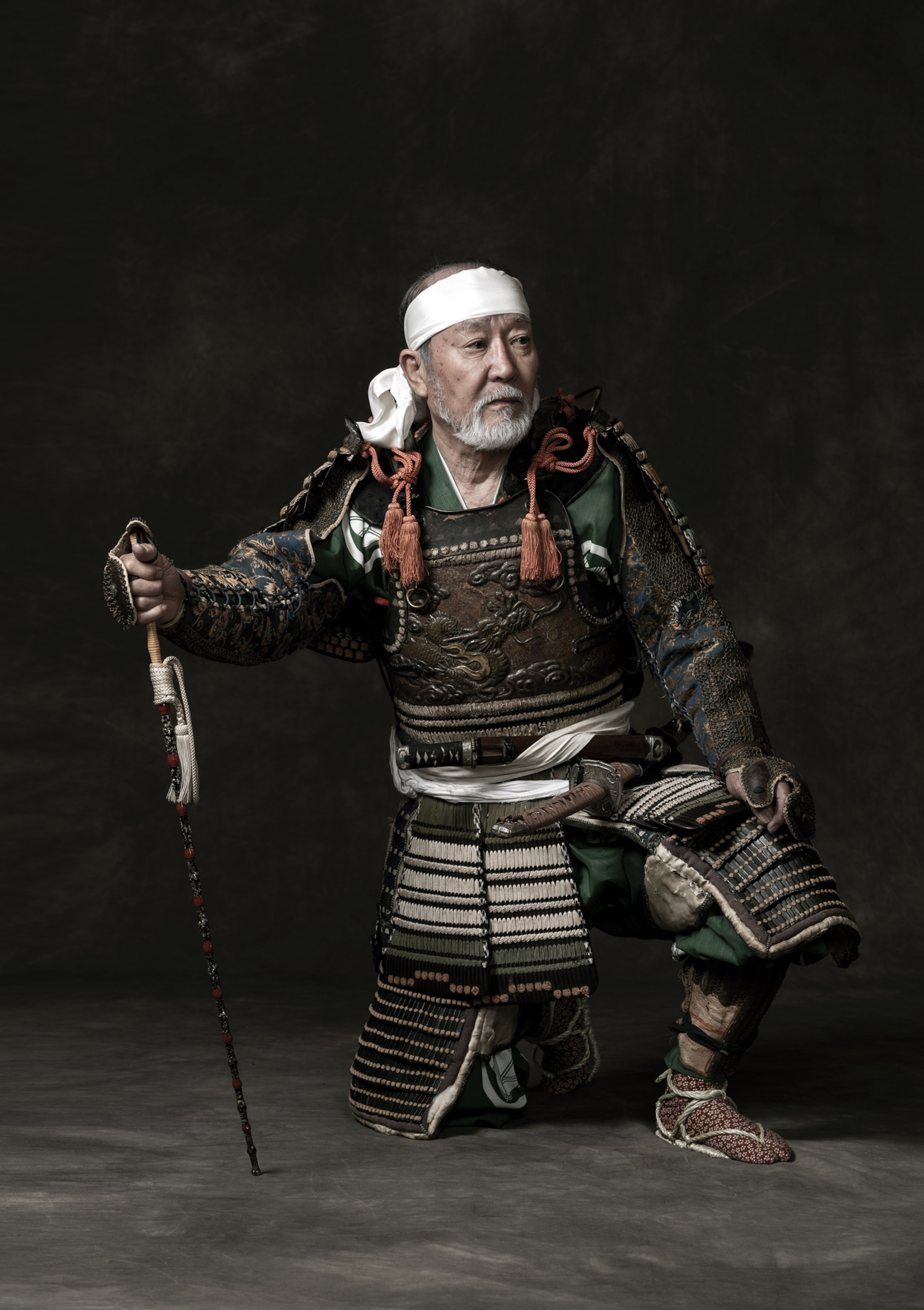 Picture of man in samurai costume and white headband on his one knee.