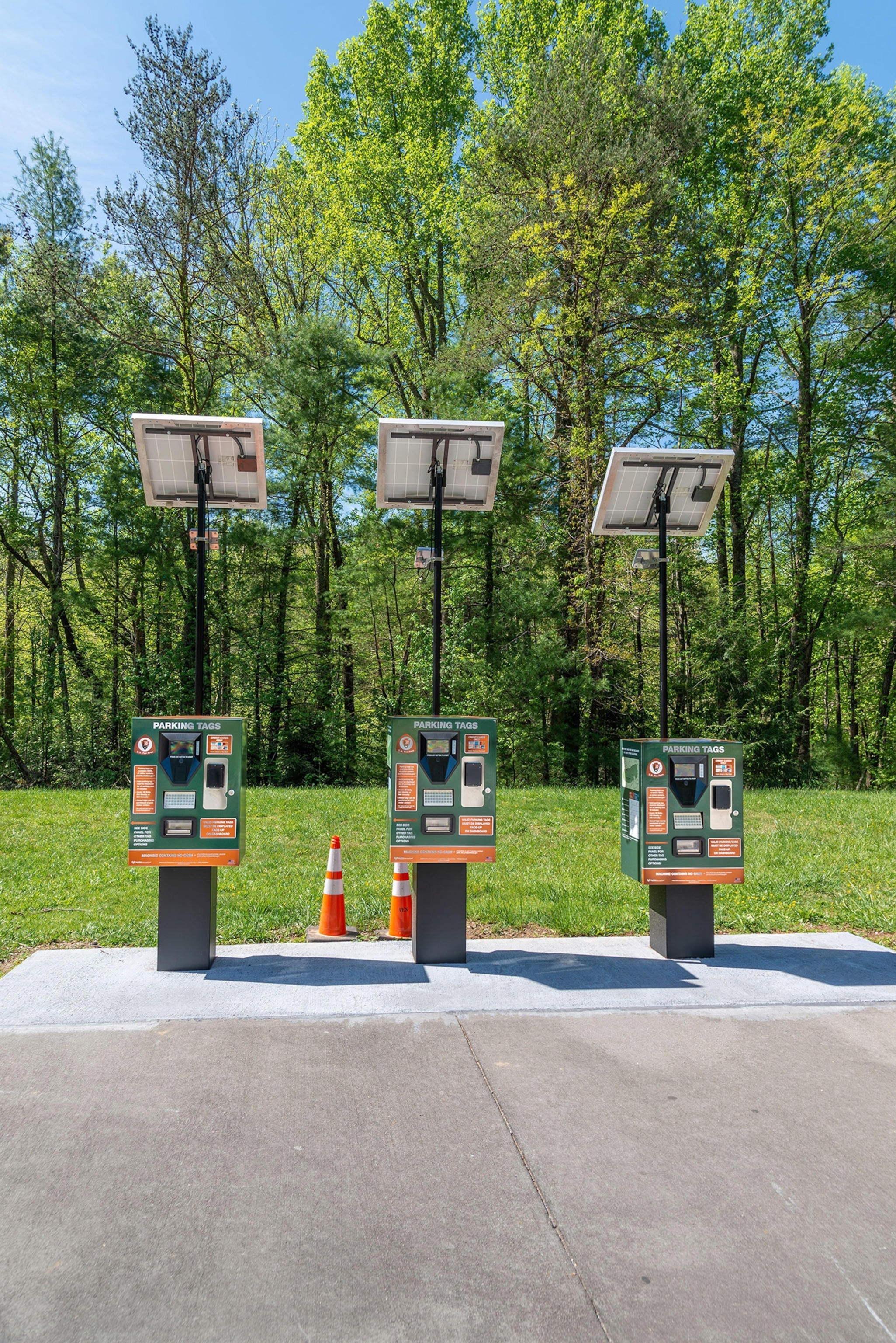 Lush green trees and blue skies in the background and electirc car charges in front.