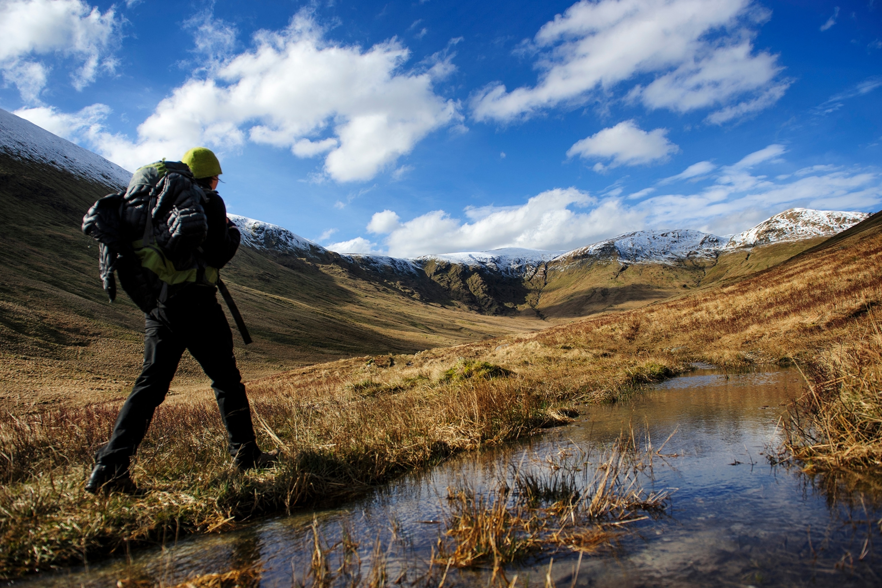 a man with camping gear hiking up a hill