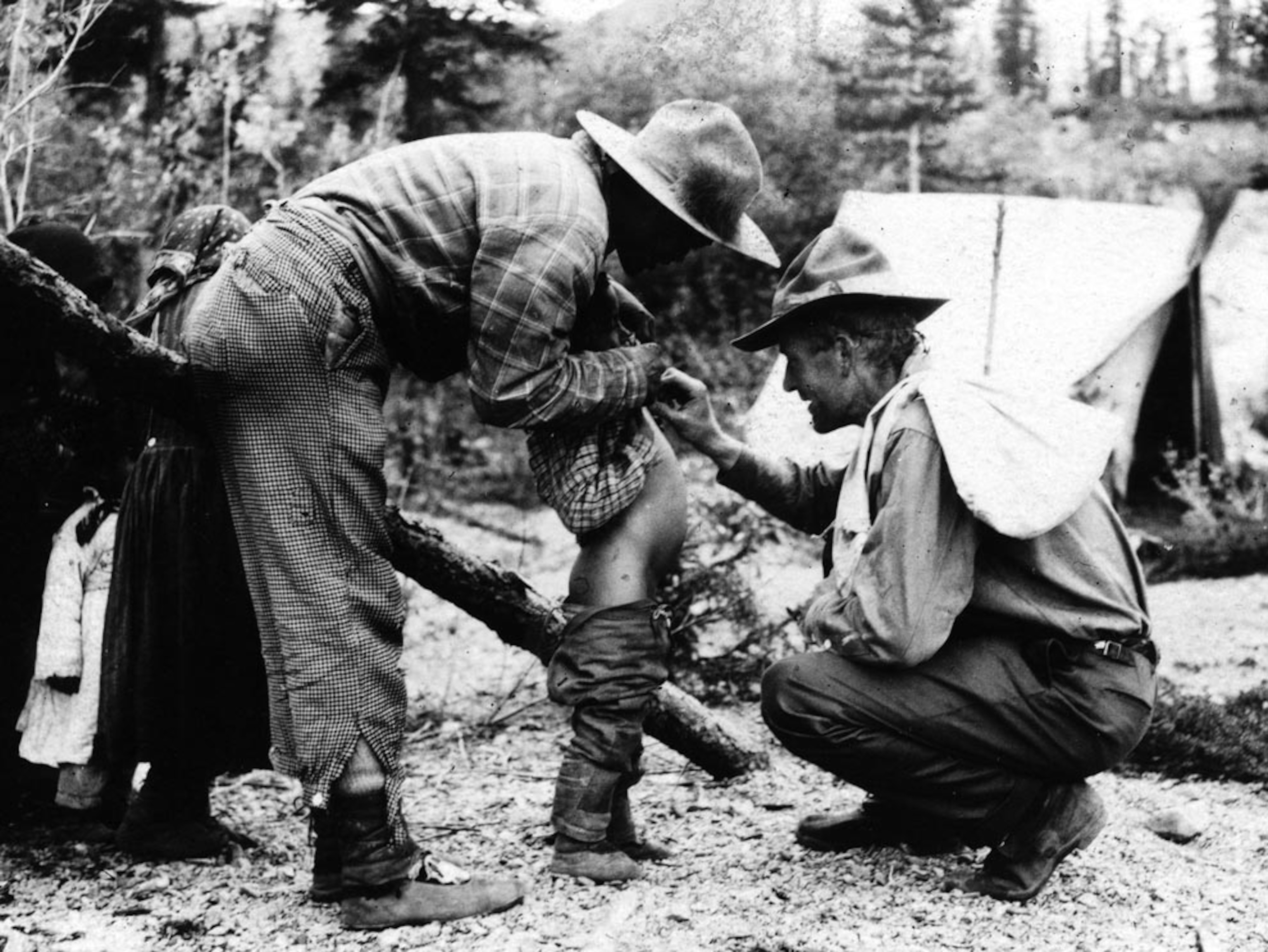 Two men examining a Native American boy