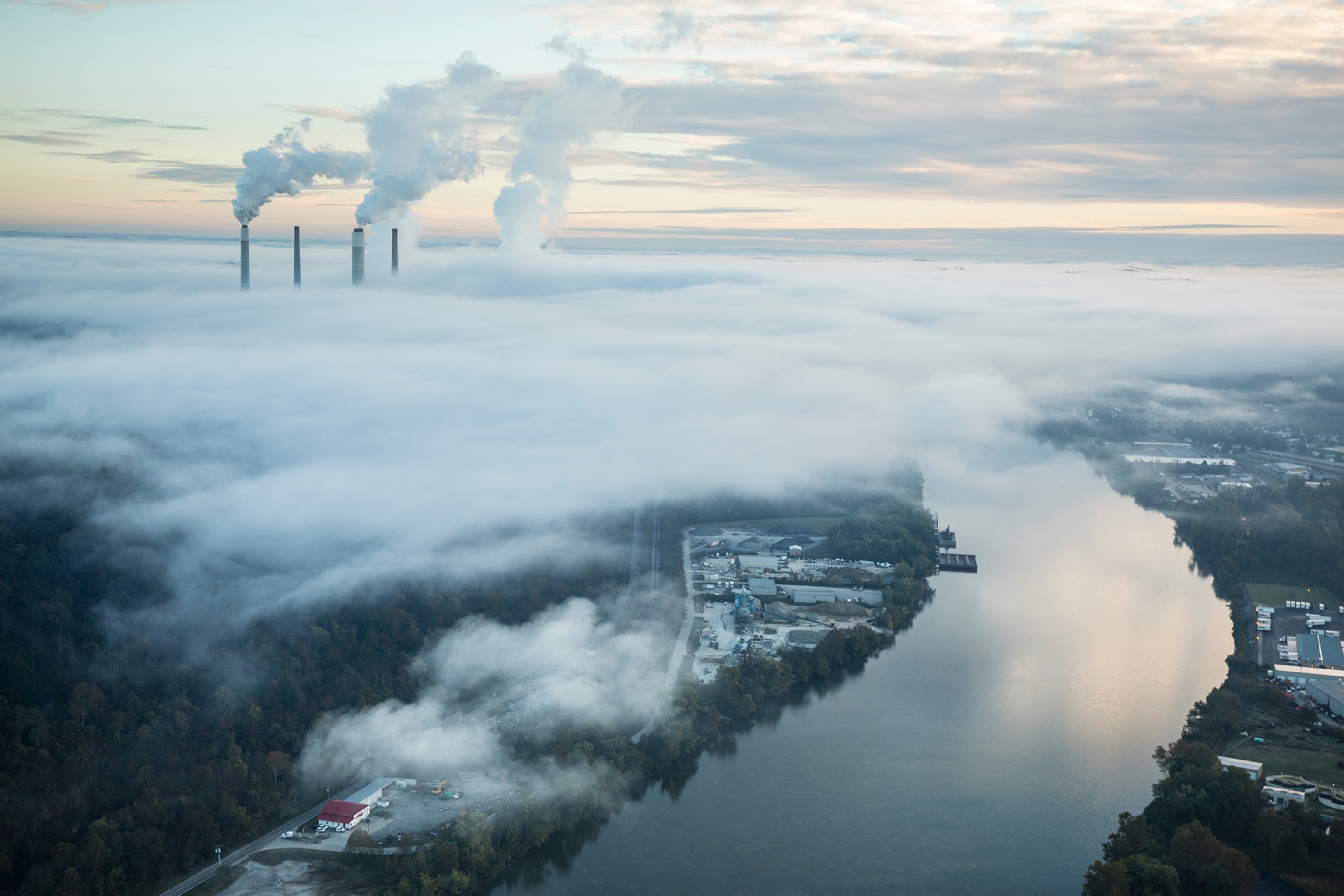 steam and smoke rise from the cooling towers and chimneys of a power plant.