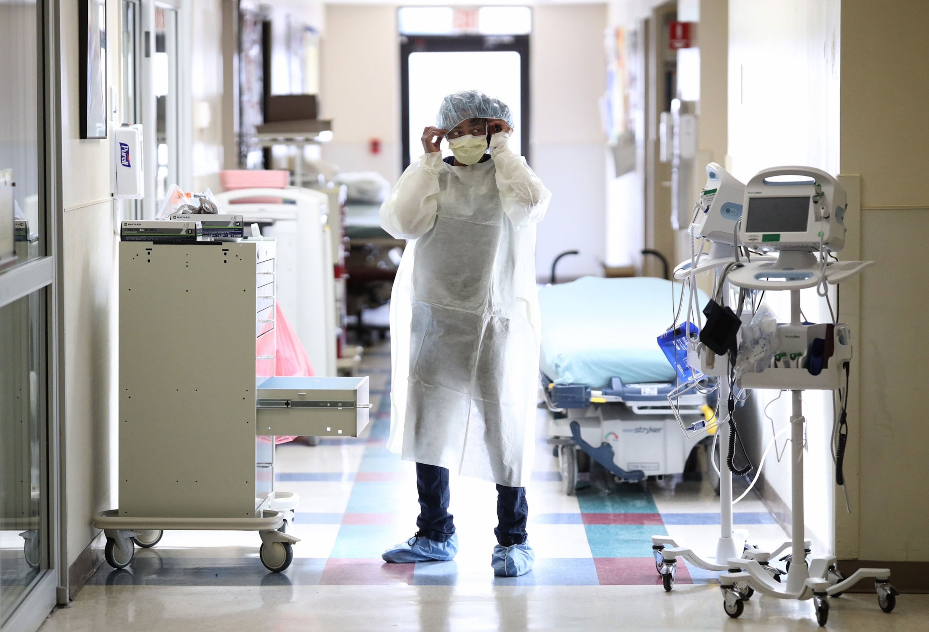 a nurse fixing her mask in a bright hallway