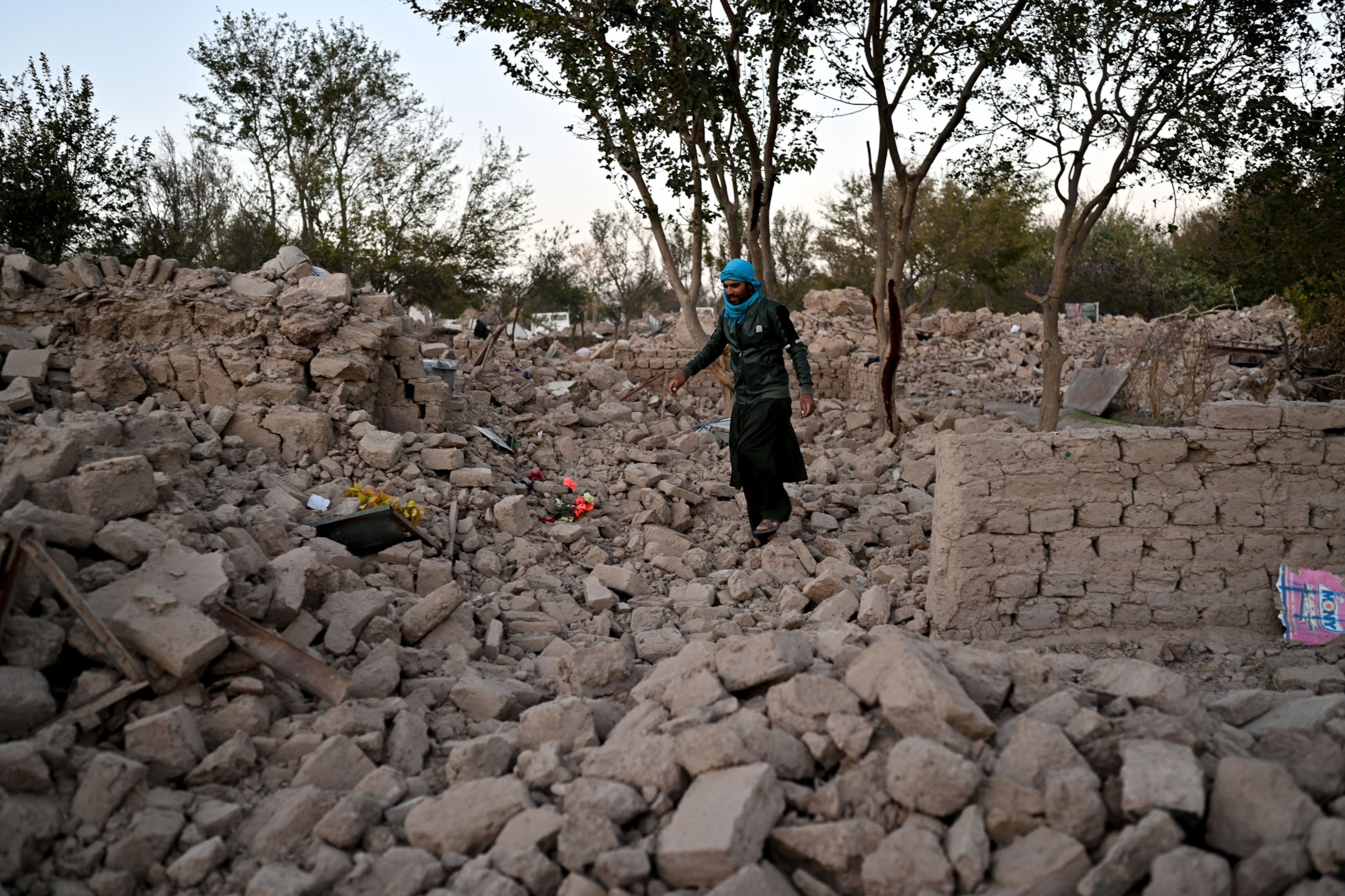 a man walks around the rubble of a stone home