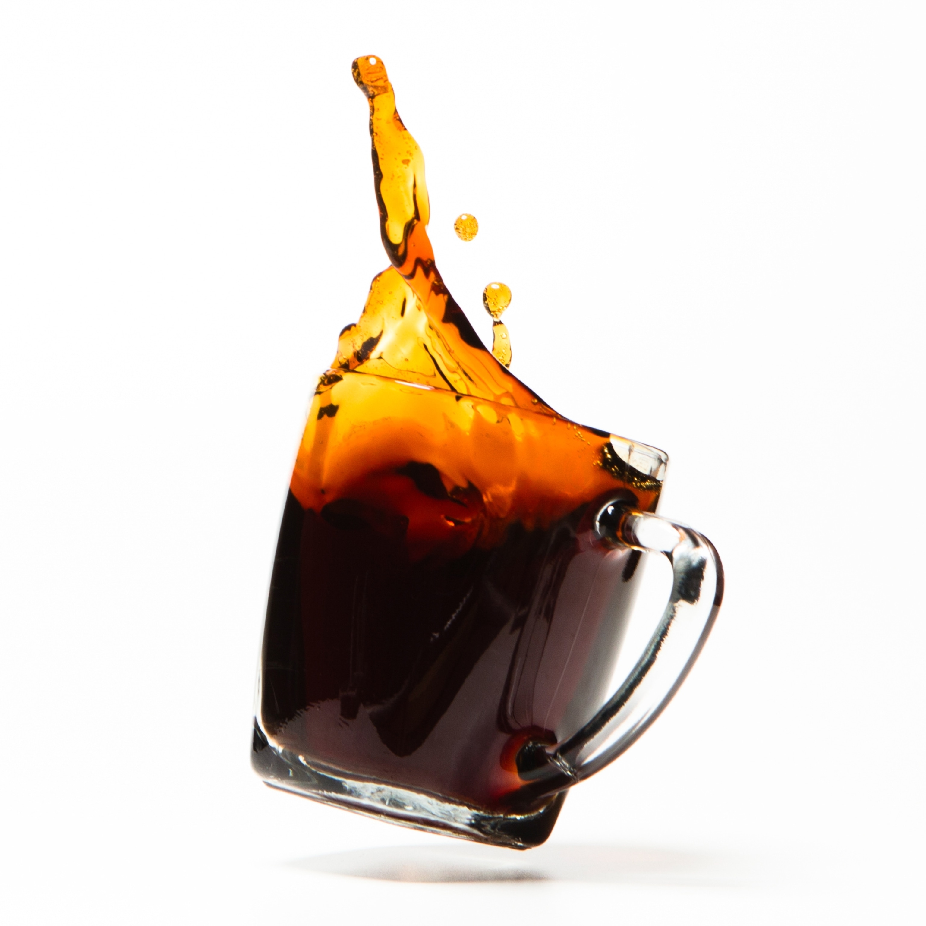 Coffee splashing out of a clear mug.