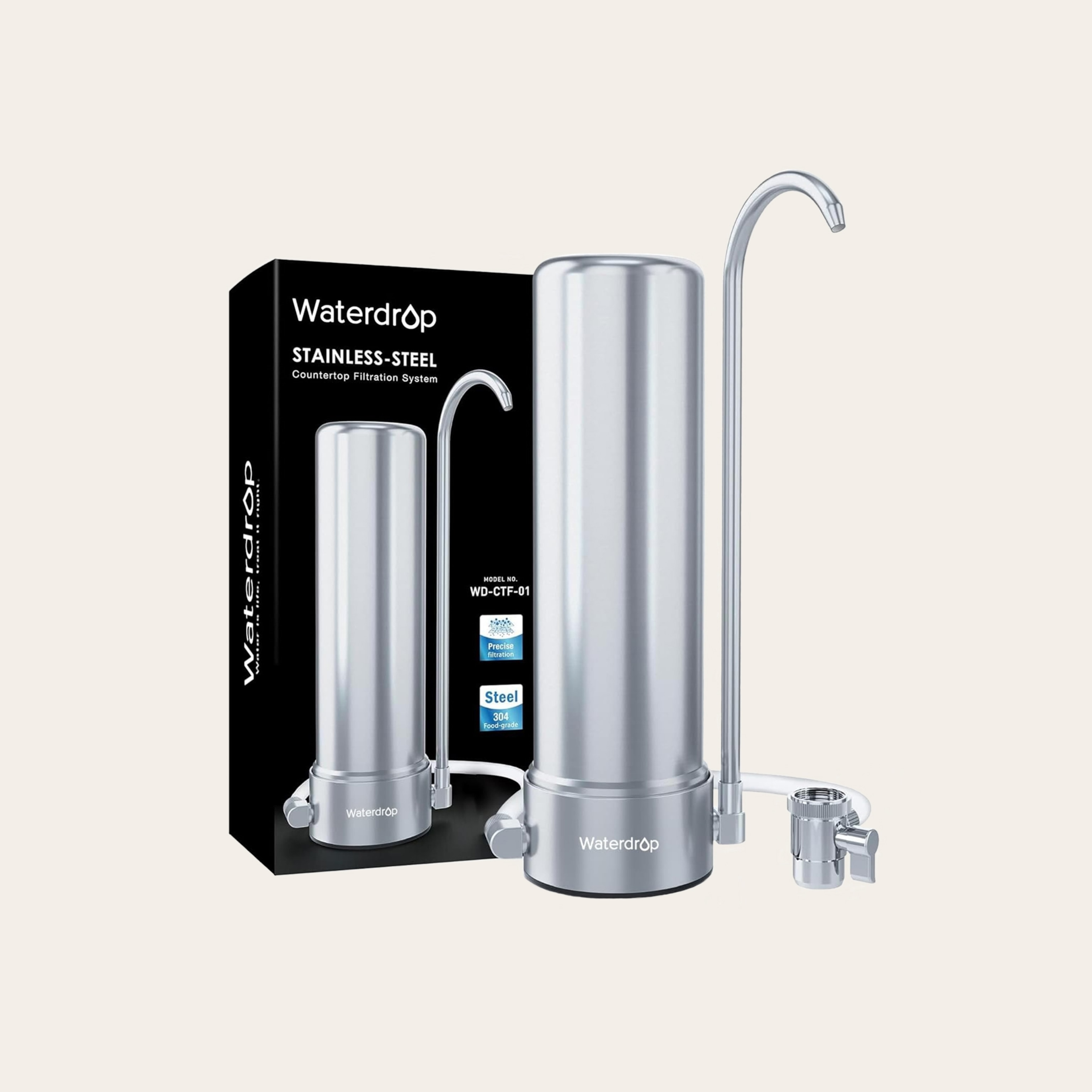 A metal, cylindrical, counter-top water filter with a long narrow spout, against a tan background.