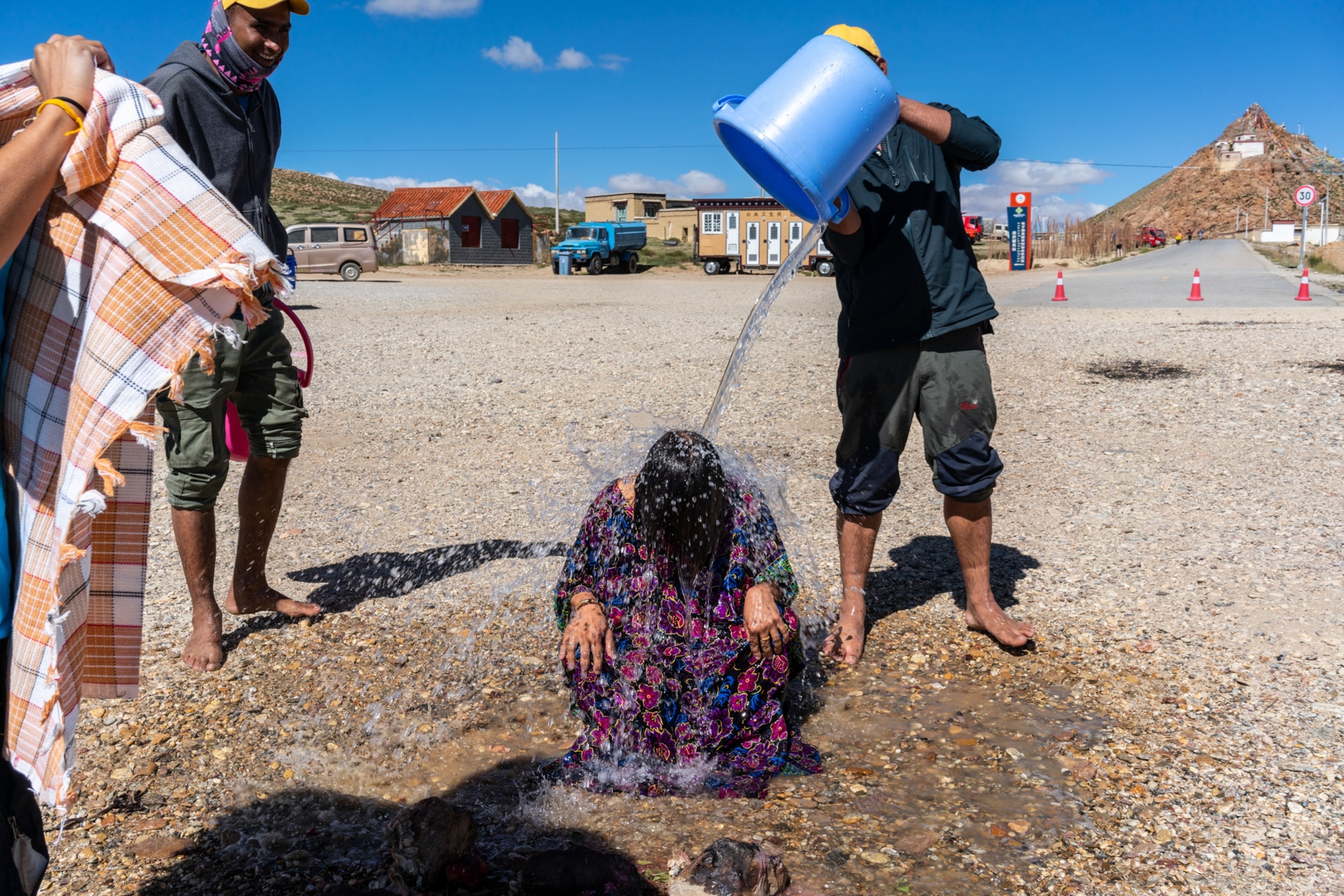 a man pouring a bucket of water over a kneeling woman