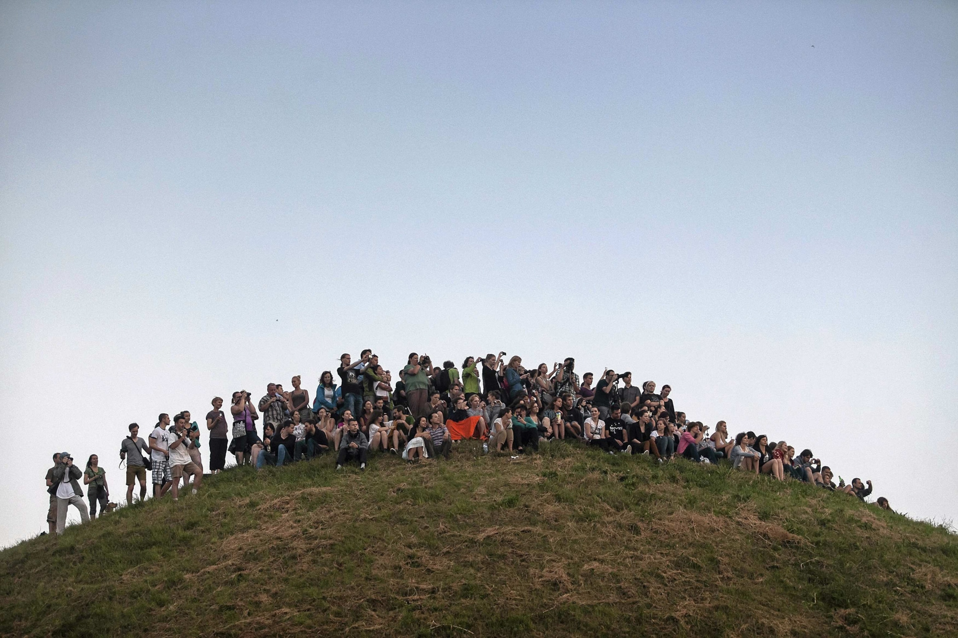 people gathered to watch the sunrise from a mound near Krakow, Poland