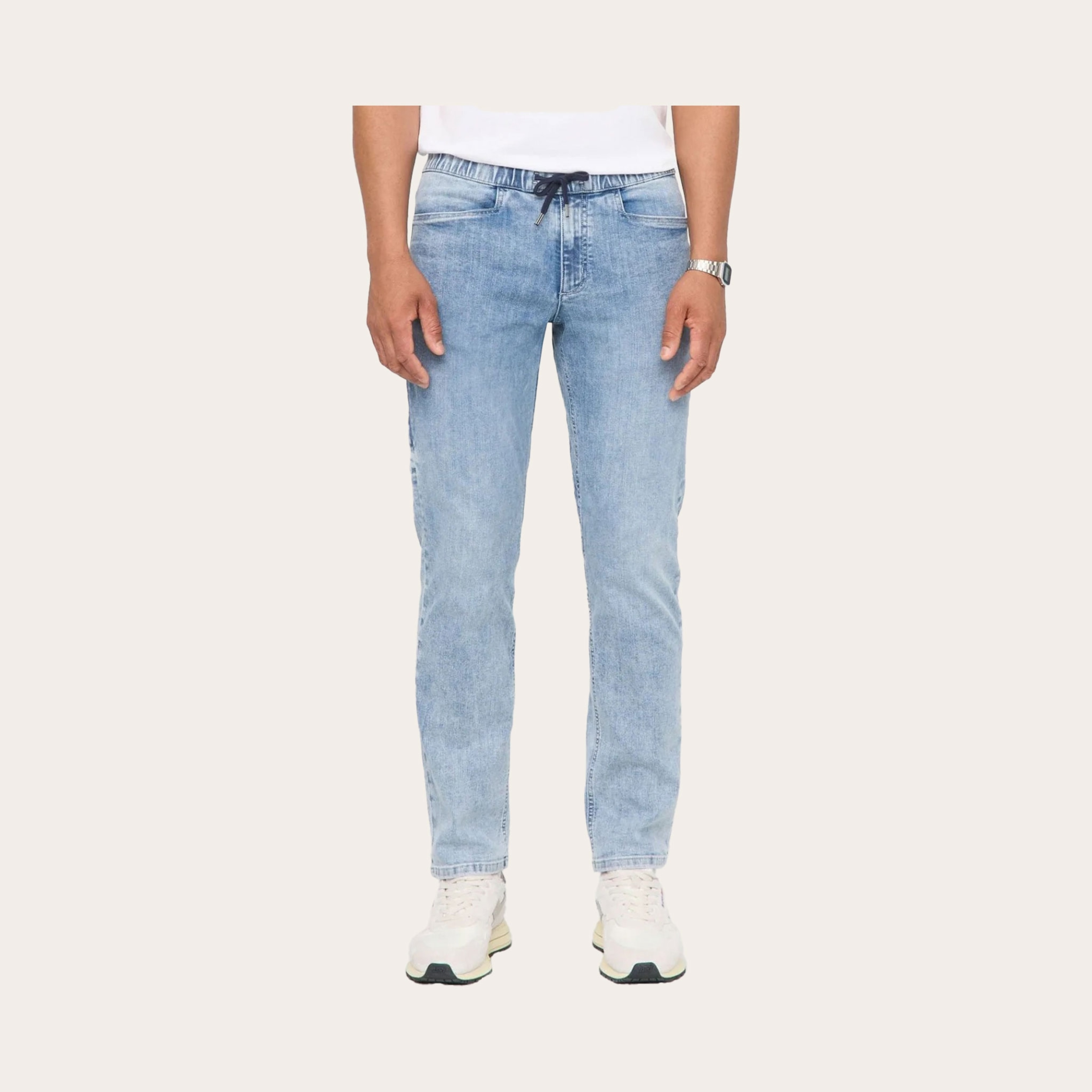 Man wearing light washed jean pants placed on a tan background.