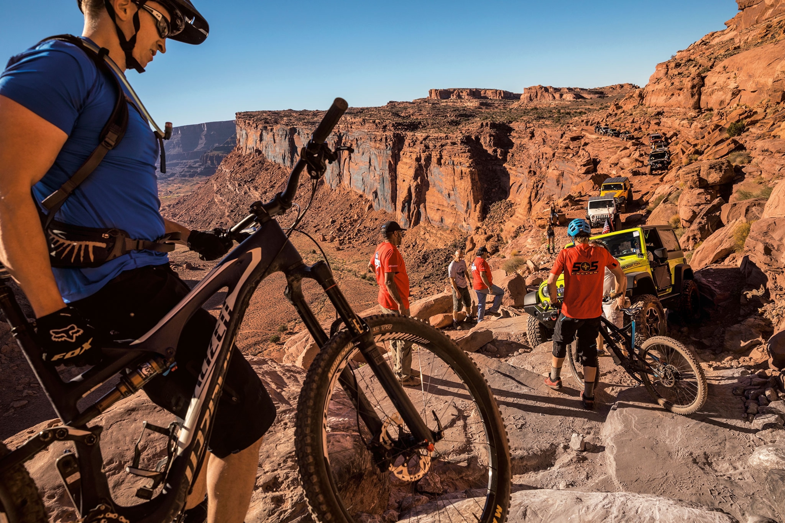 A group of men with bikes on a dirt and rock trail in a canyon