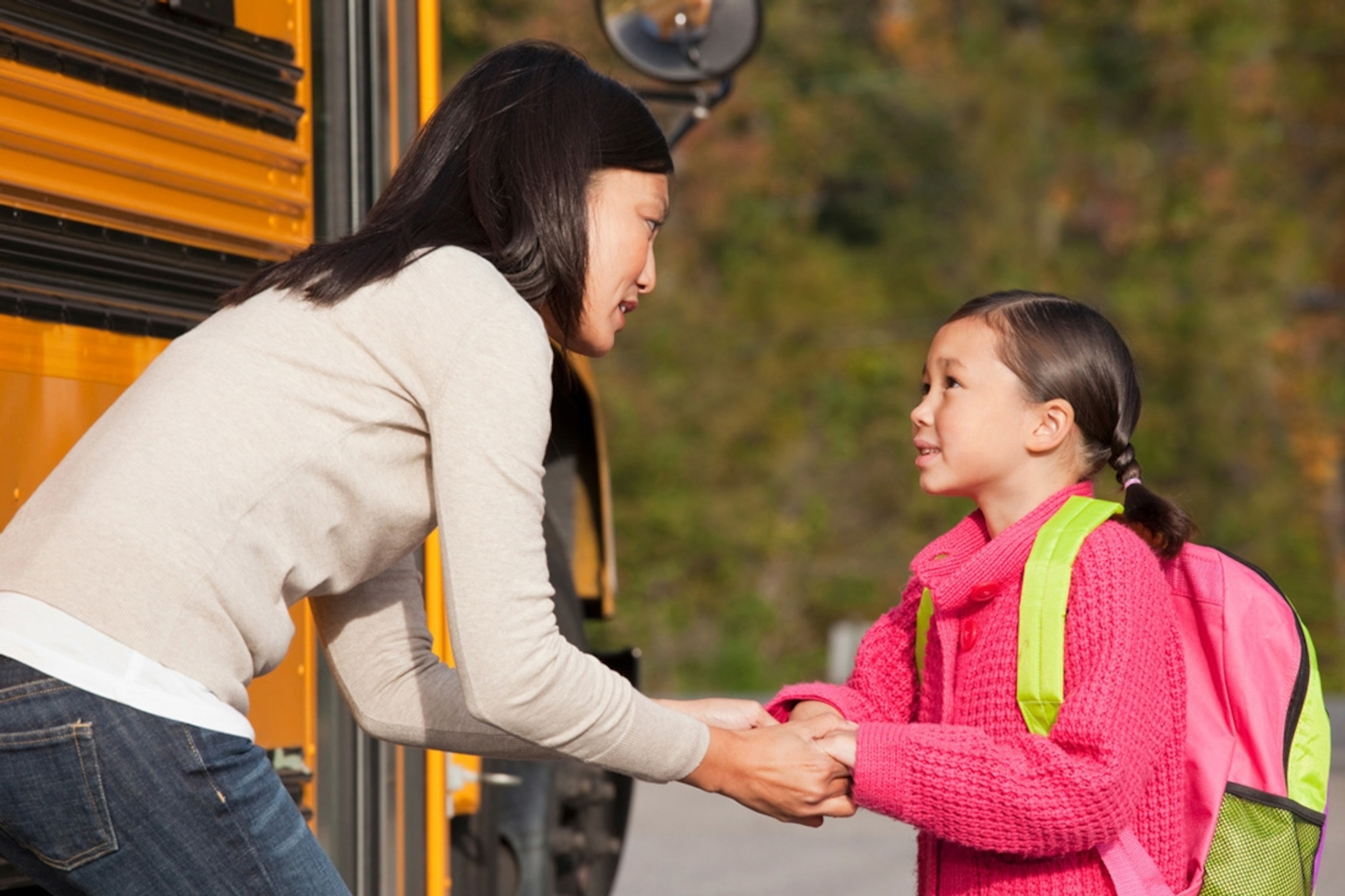 Mother talking to daughter as she gets on the school bus.