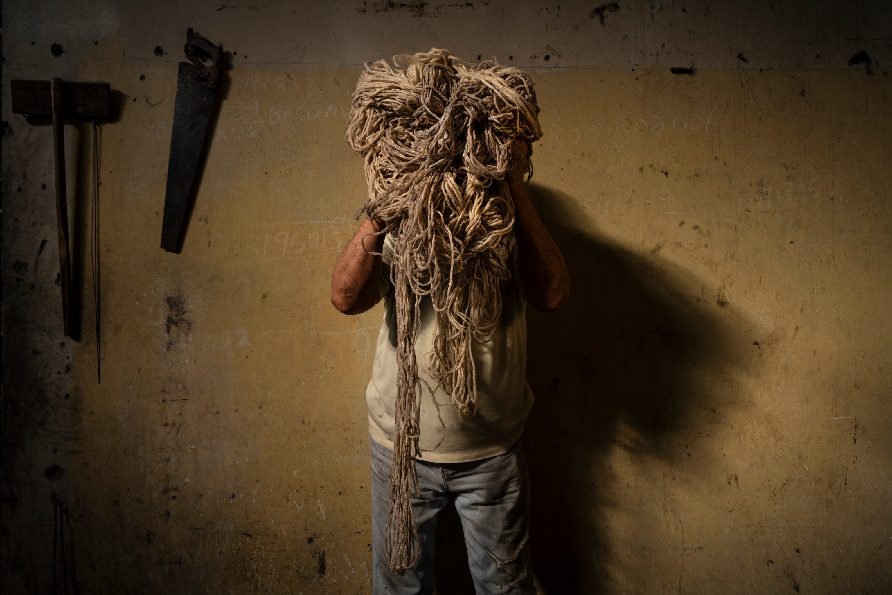 man holding up a messy knot of yarn in front of his face