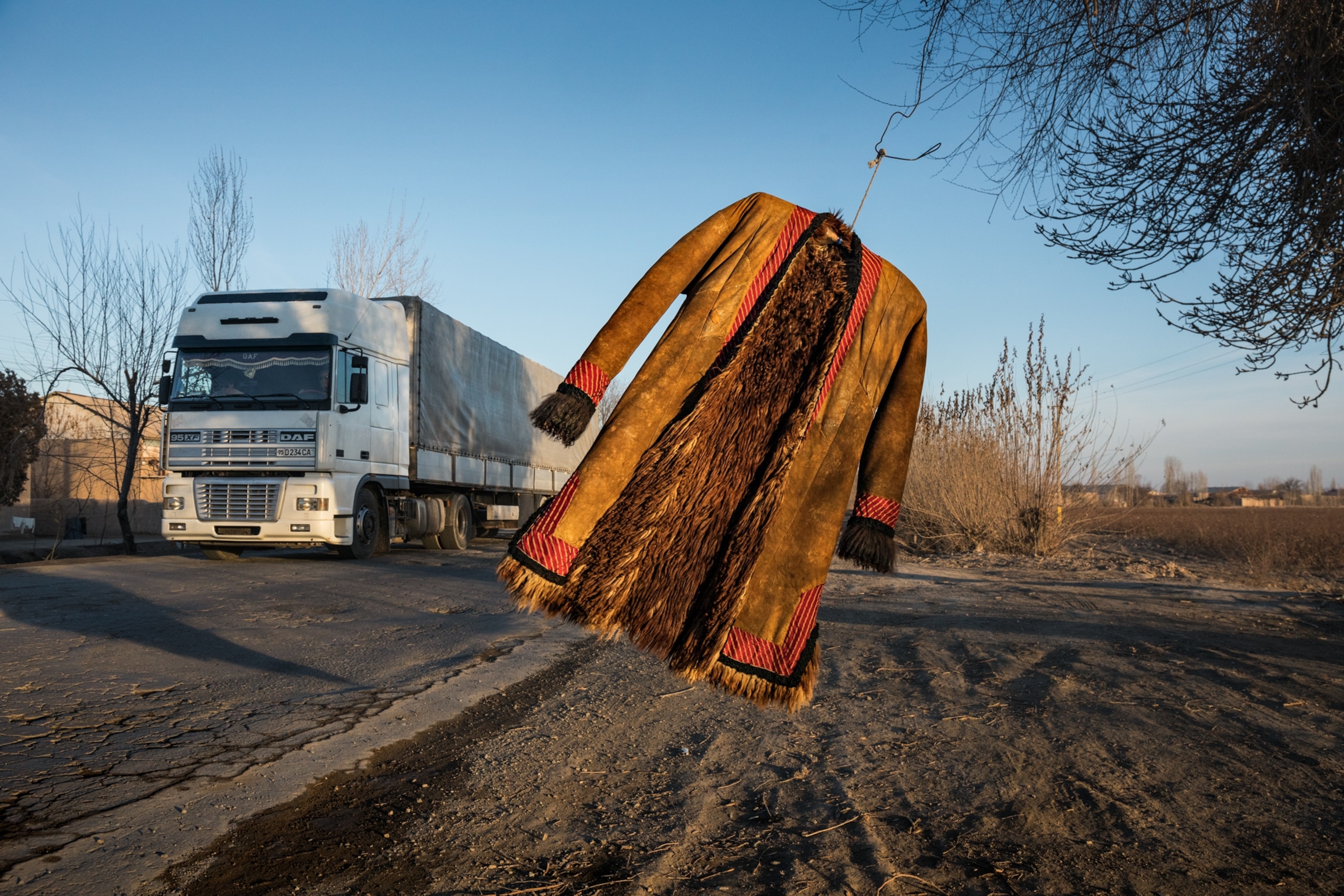 a traditional Uzbek yellow and red coat hanging on branches and swaying in the wind