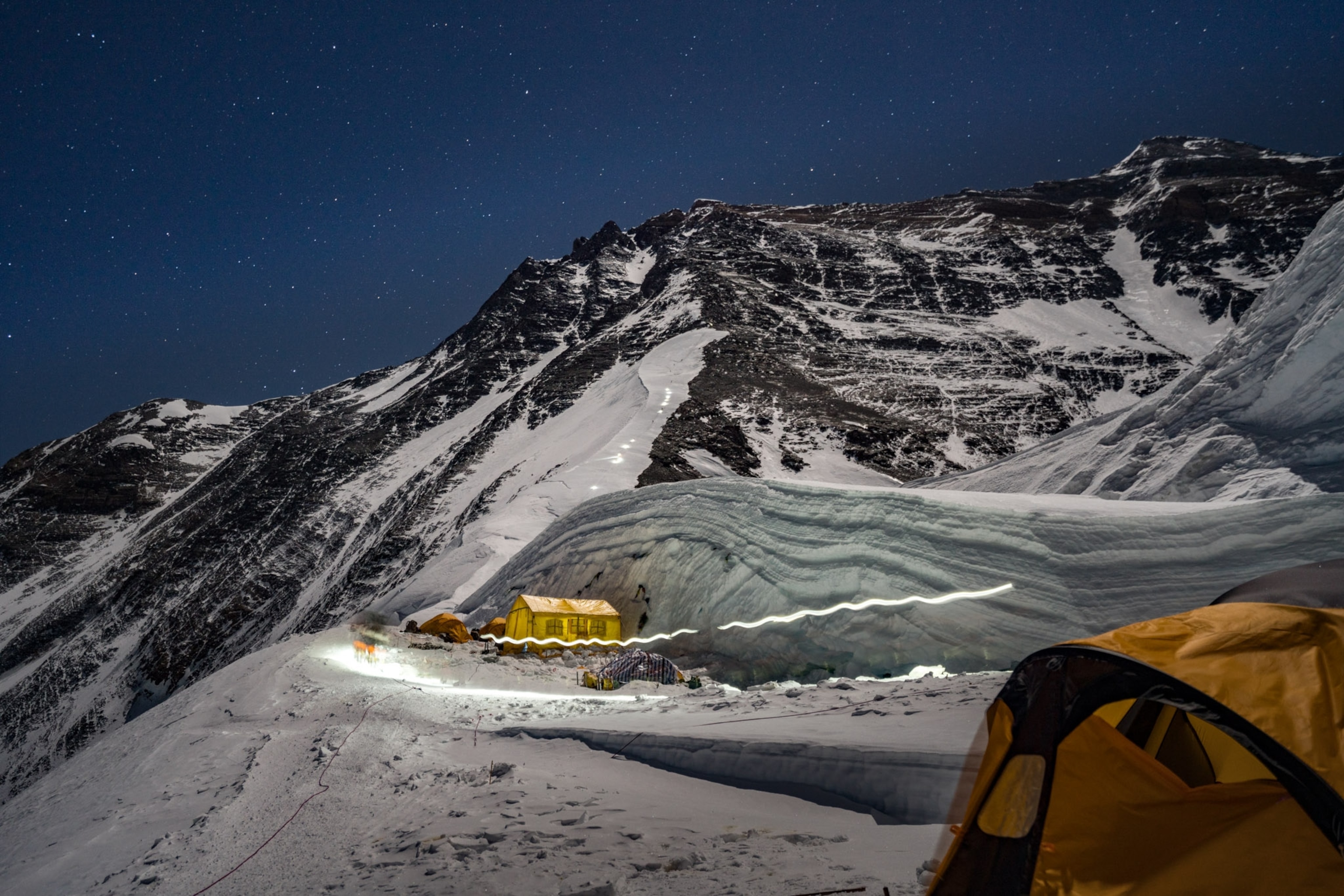 a yellow tent illuminated by headlamps at night