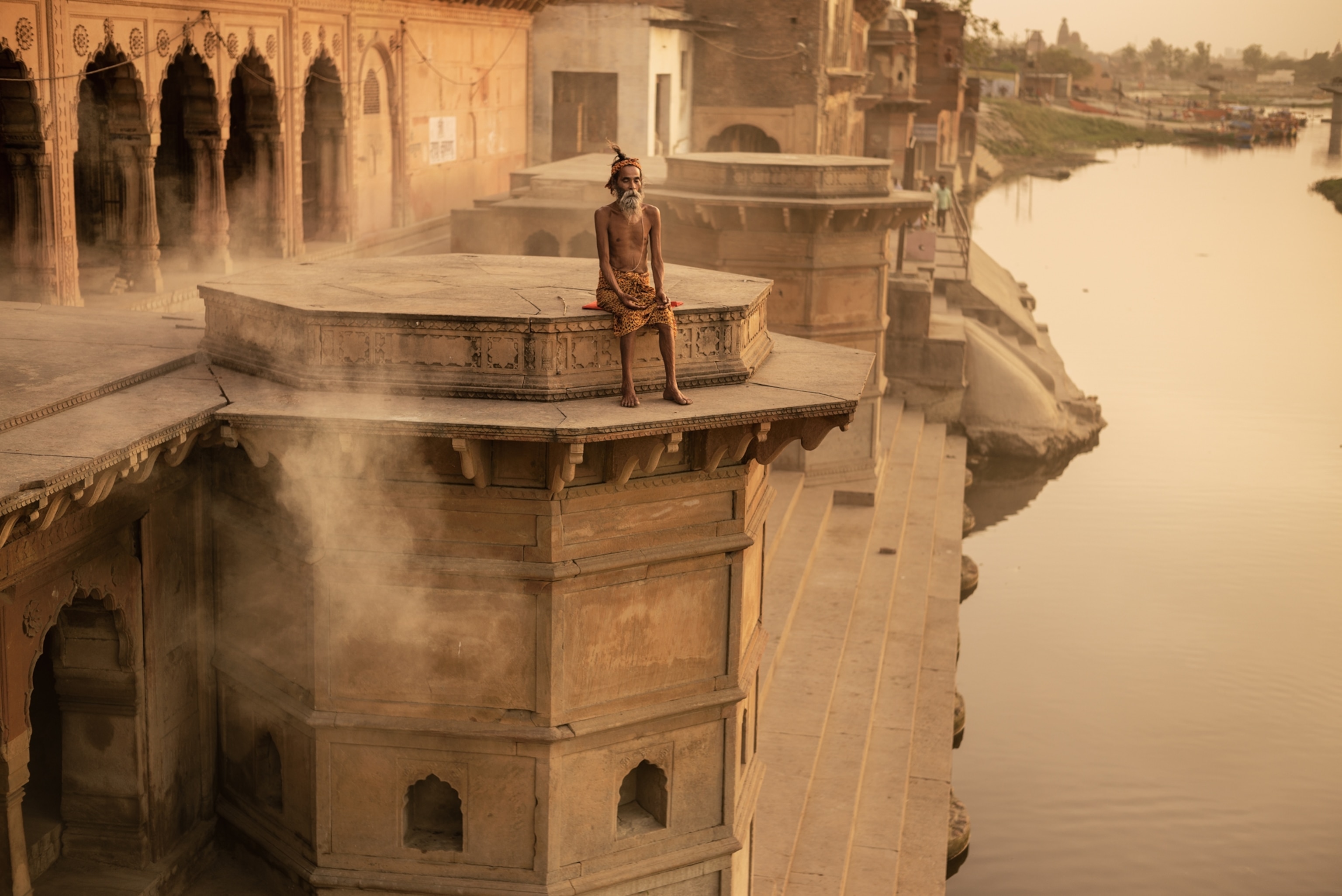 man meditating atop of tall tower above river