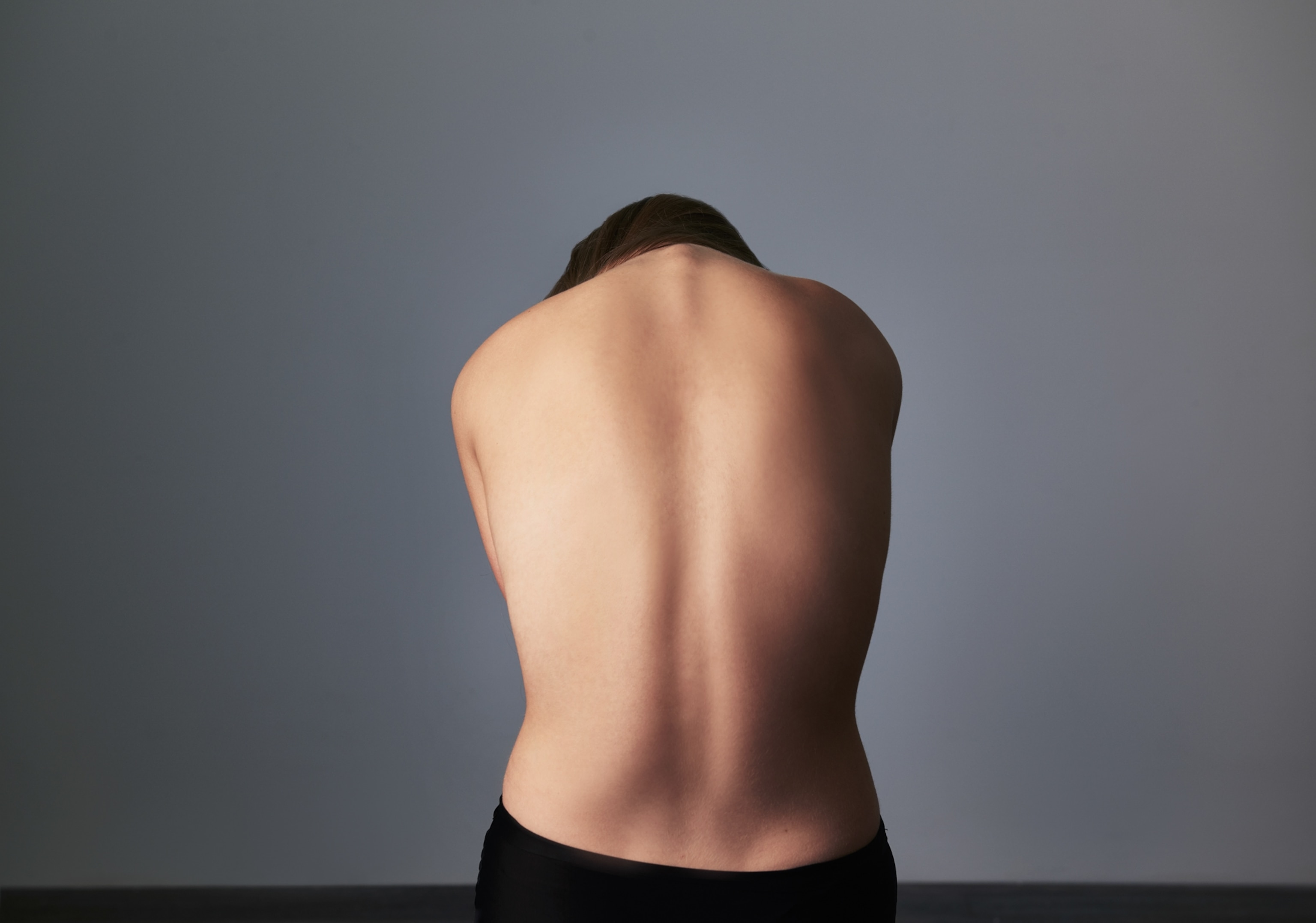 A woman's bare back, exposed while she hunches over.