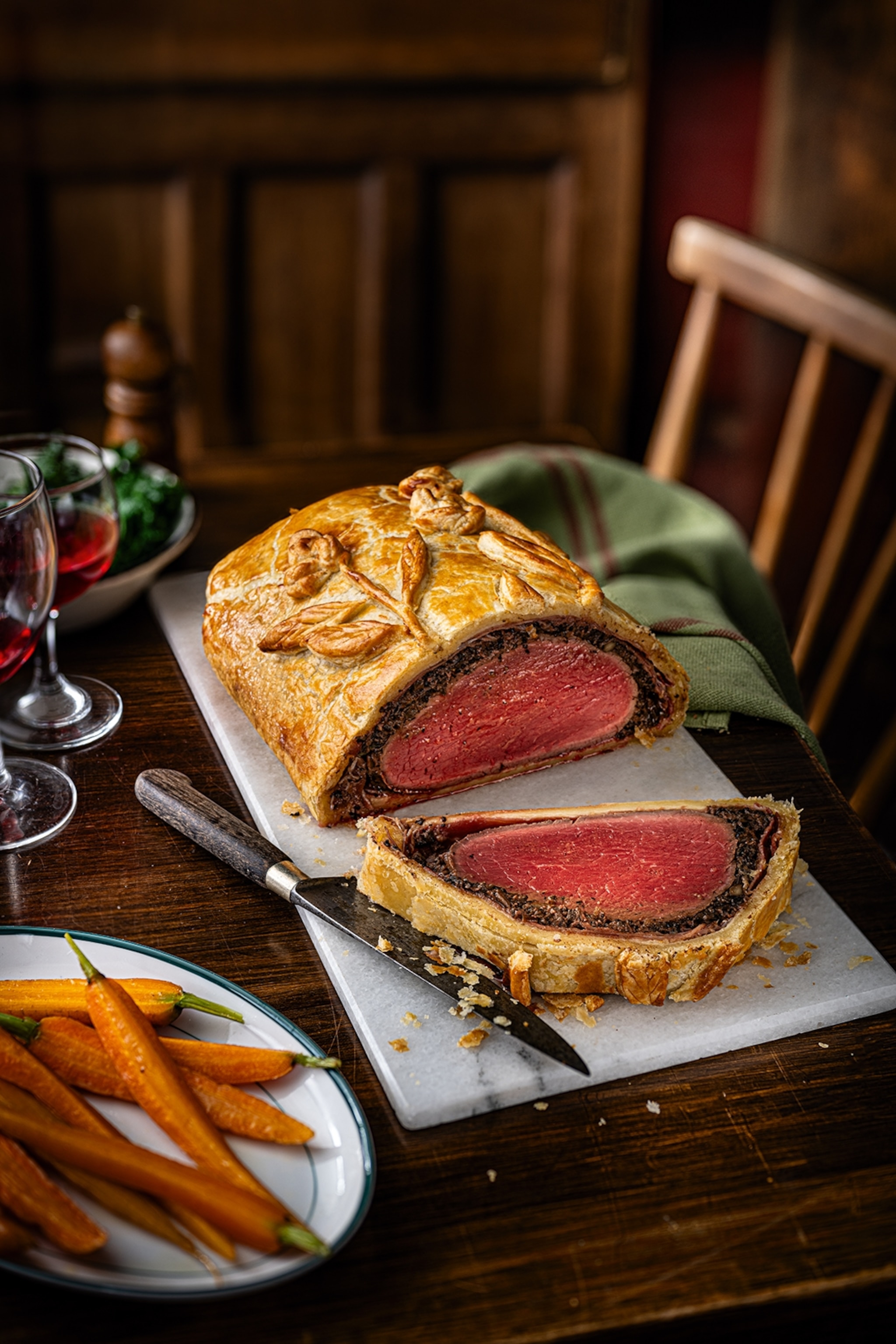 Sliced beef wellington on a chopping board with a knife alongside
