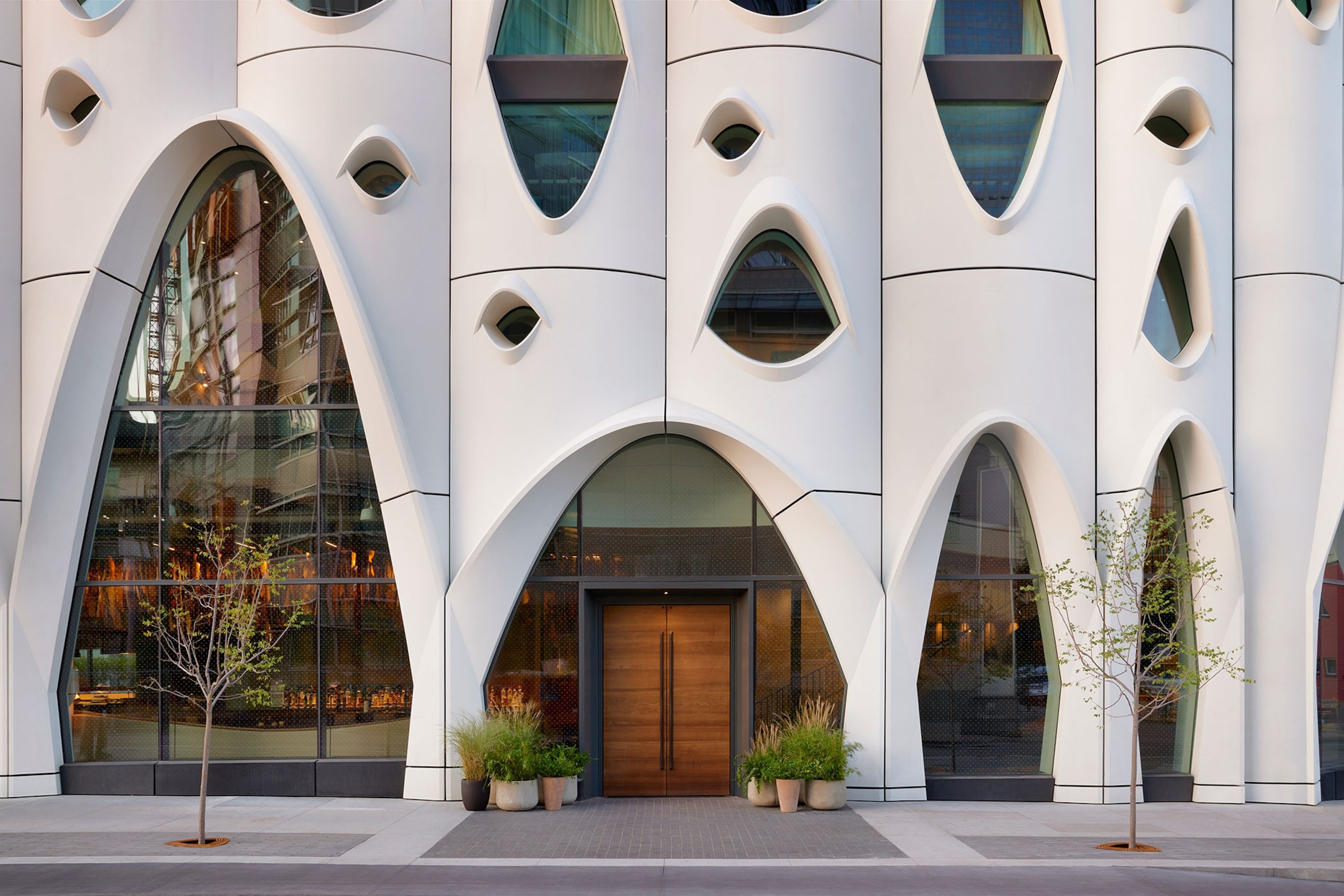 Front of white hotel with unique arched entrance and windows.