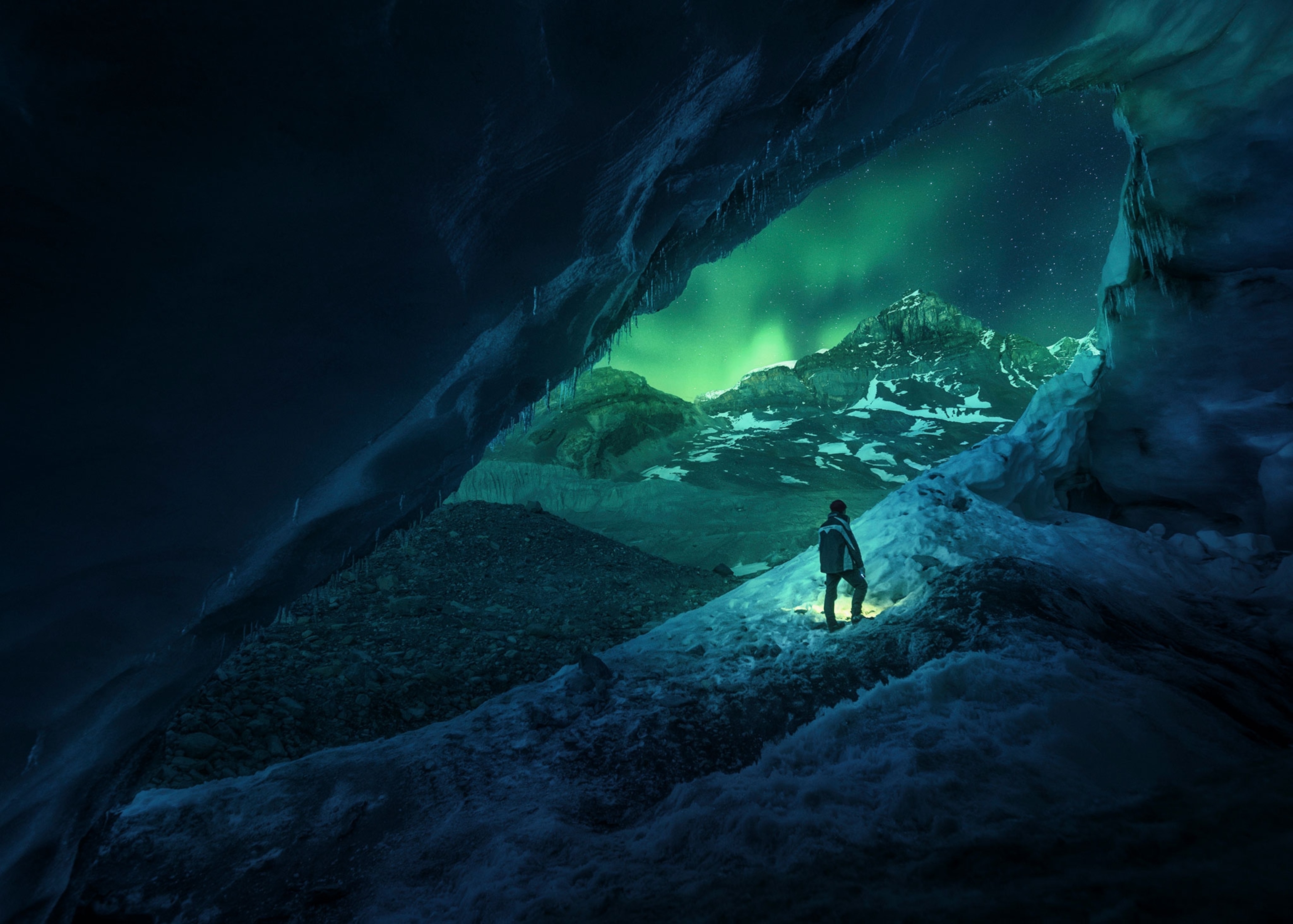 a person exploring Alberta's Athabasca cave under an aurora borealis