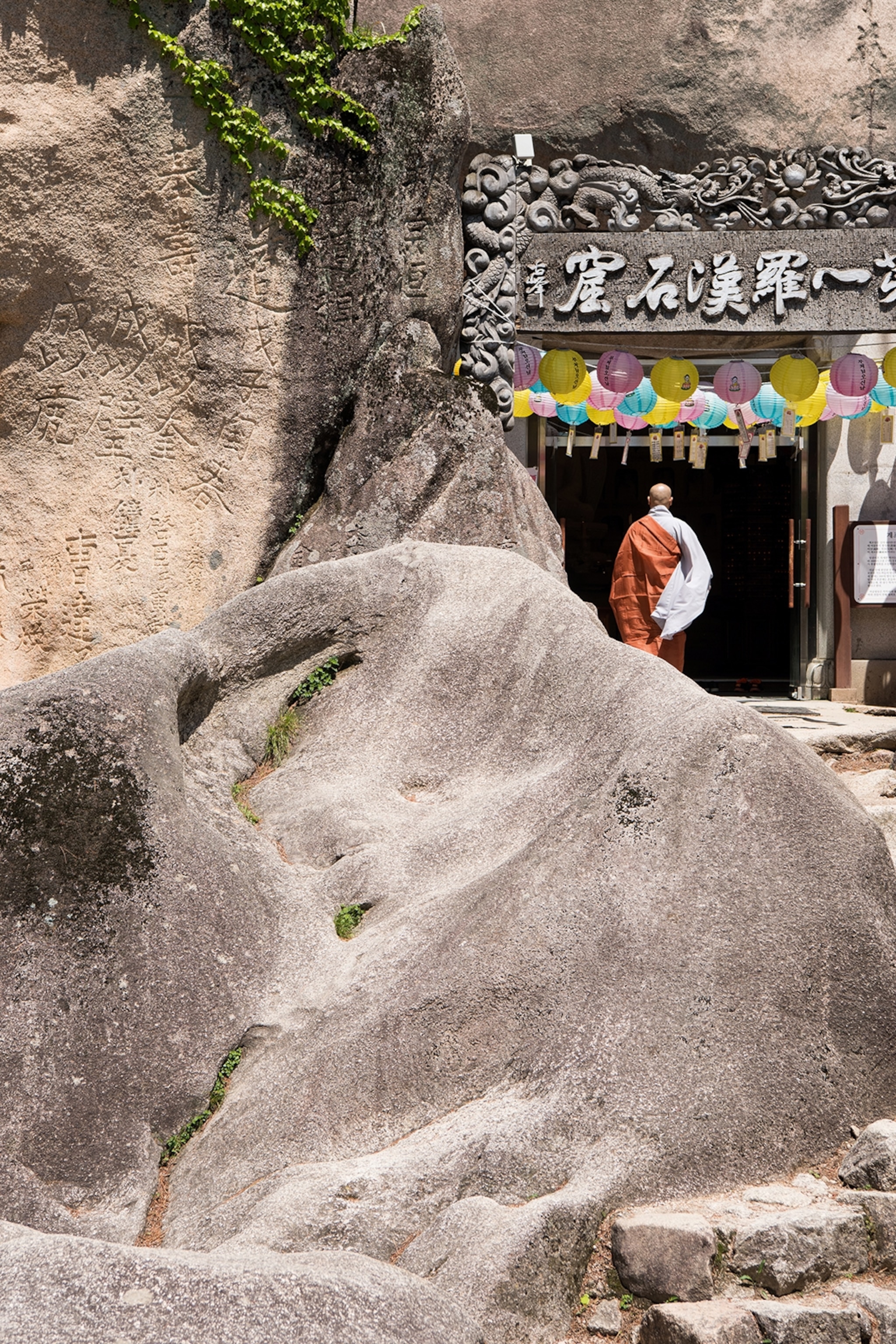 Monk walking into a grotto built into rock