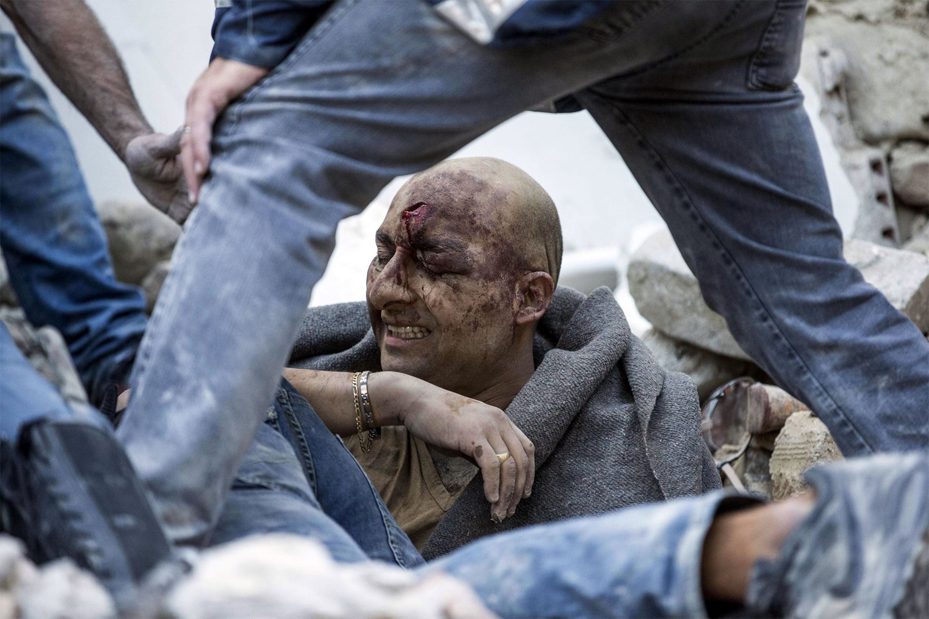 a man being lifted from the rubble after an earthquake in Italy