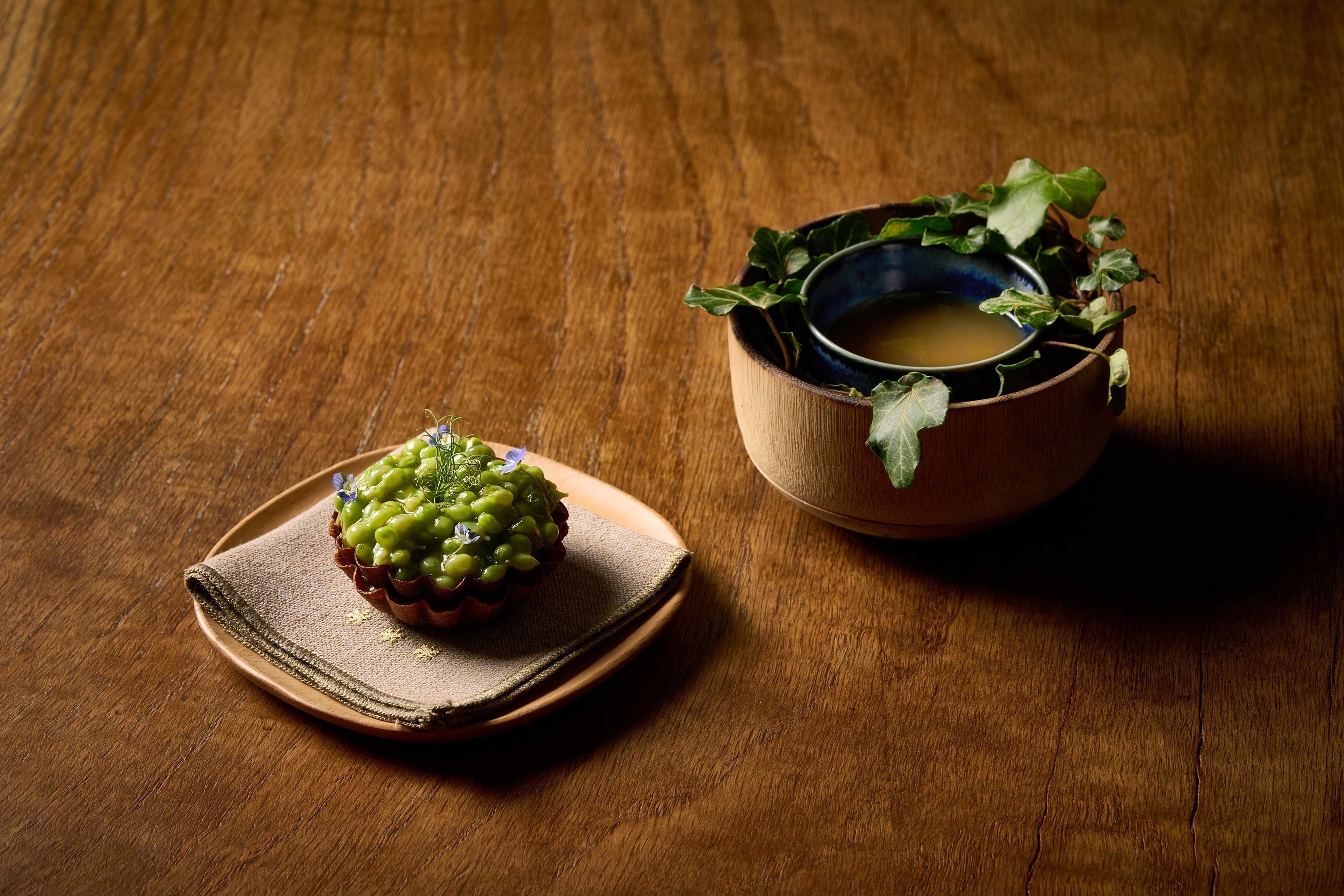 Bright green peas in a tart of crisp pastry, served with a bowl of green gel encircled by ivy
