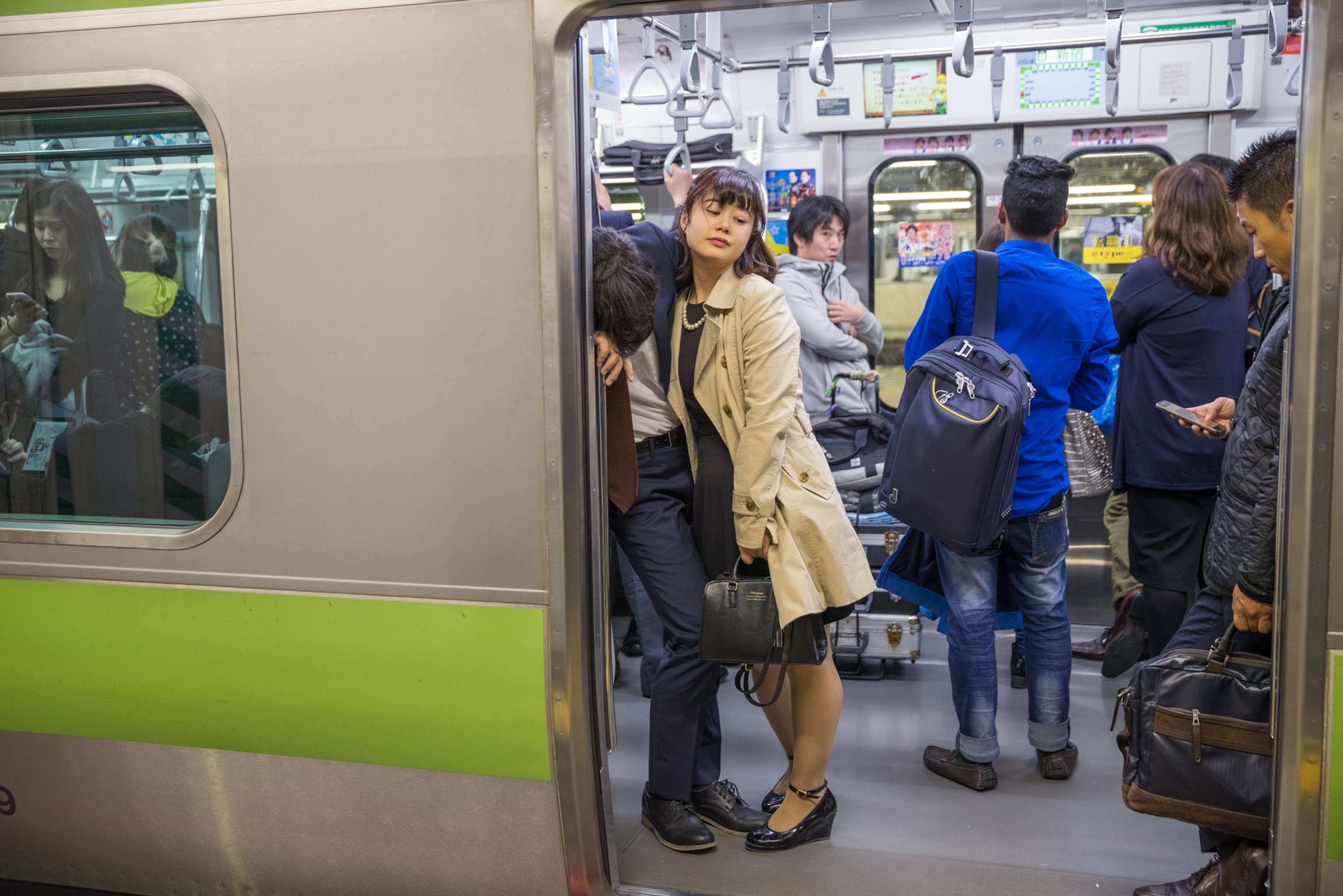 subway train door open as a man leans on a wall resting while a woman leans on him