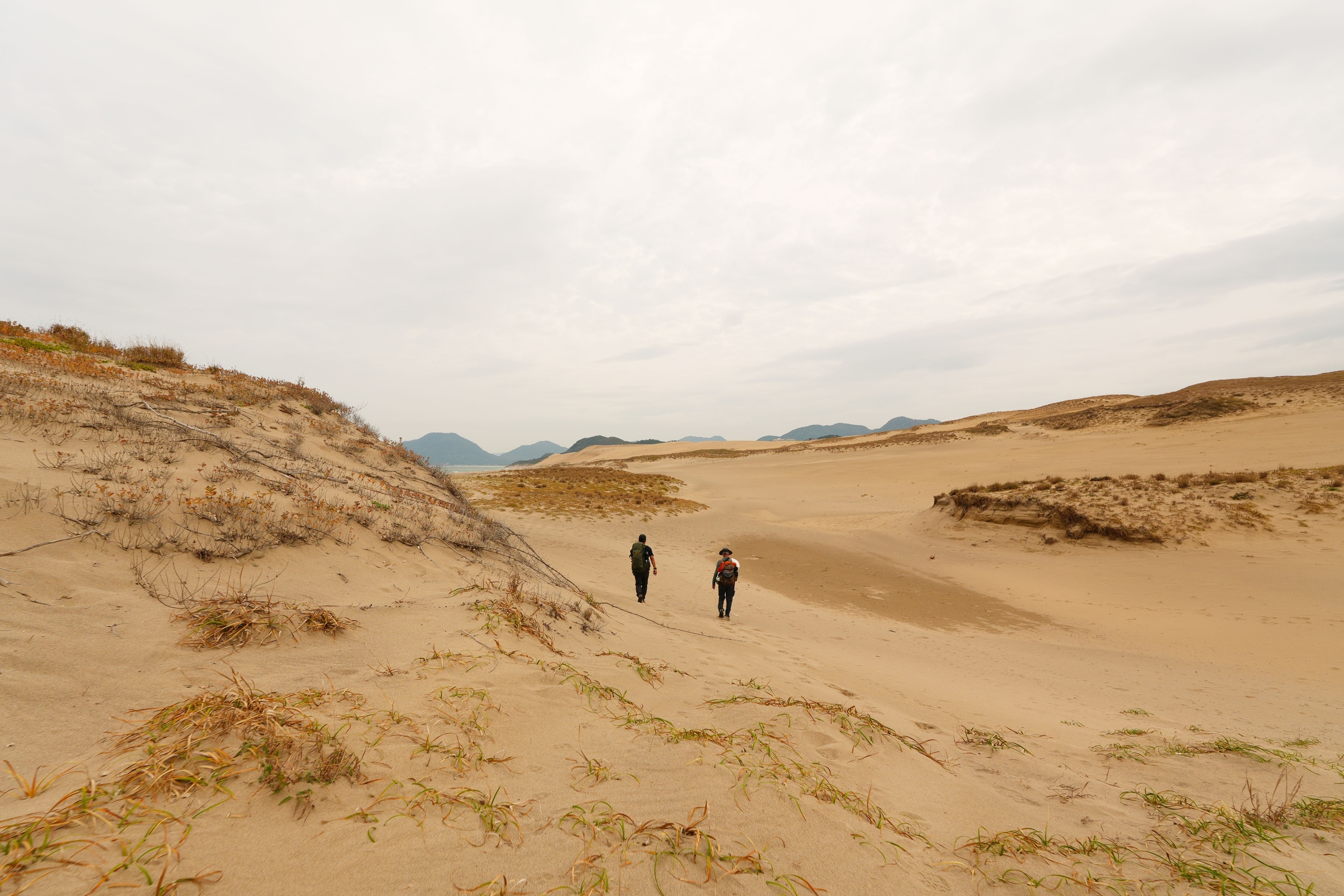 Salopek (right) and walking partner, photographer Soichiro Koriyama (left) traverse Japan’s most massive sand dunes; a surprise desert landscape border ing the Tottori Prefecture coastline.