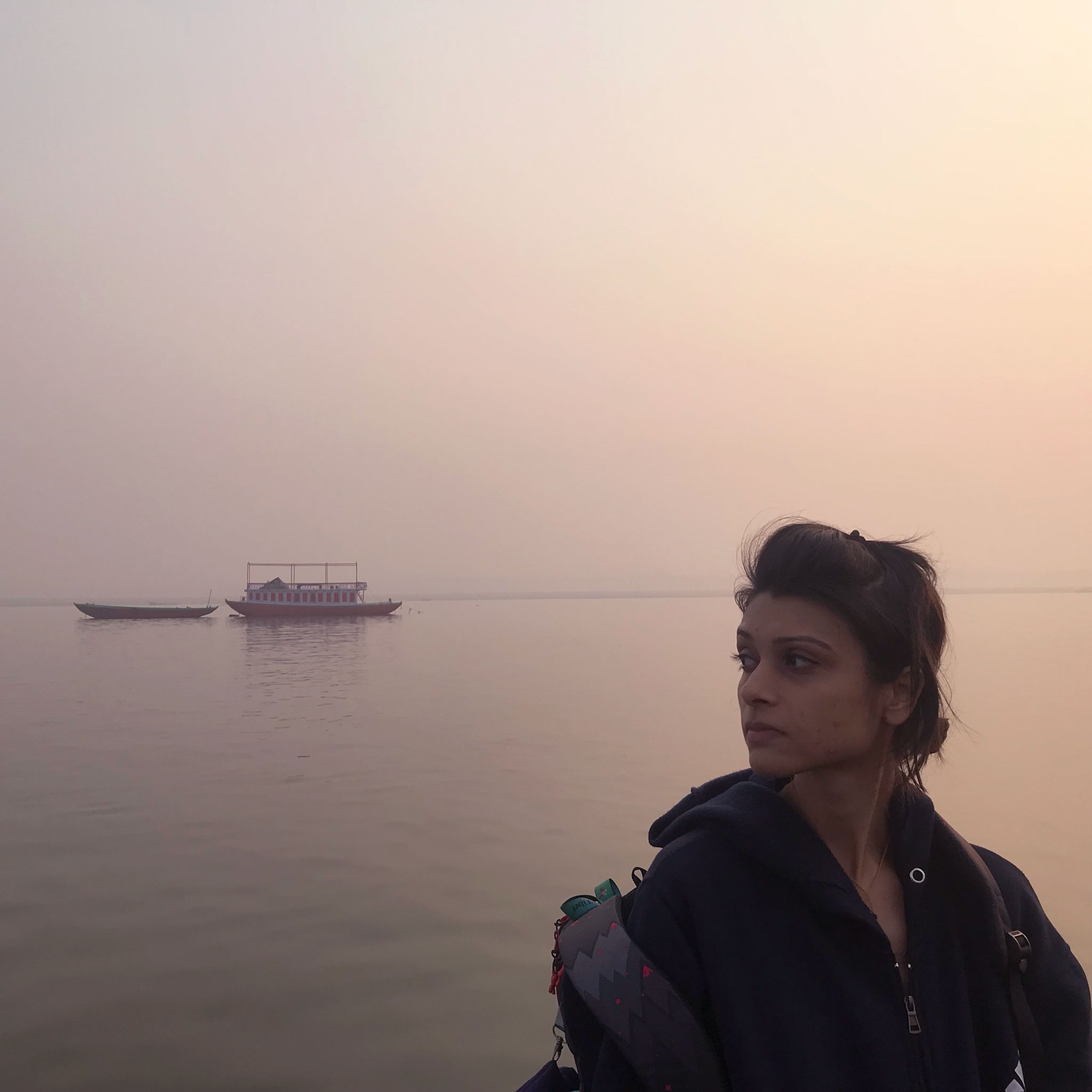 a woman on the bank of a river at sunset