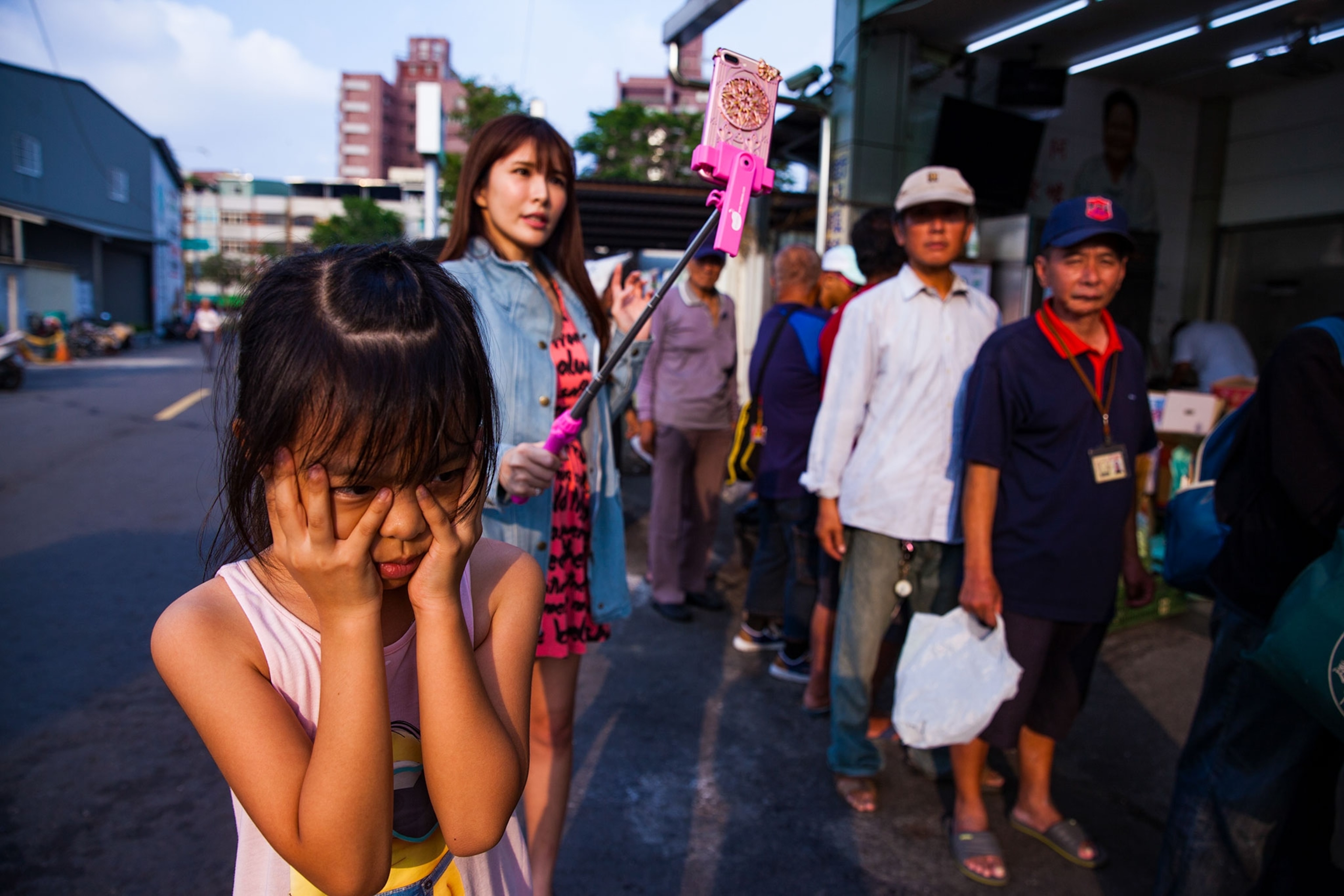 a woman livestreaming while her daughter waits for her nearby