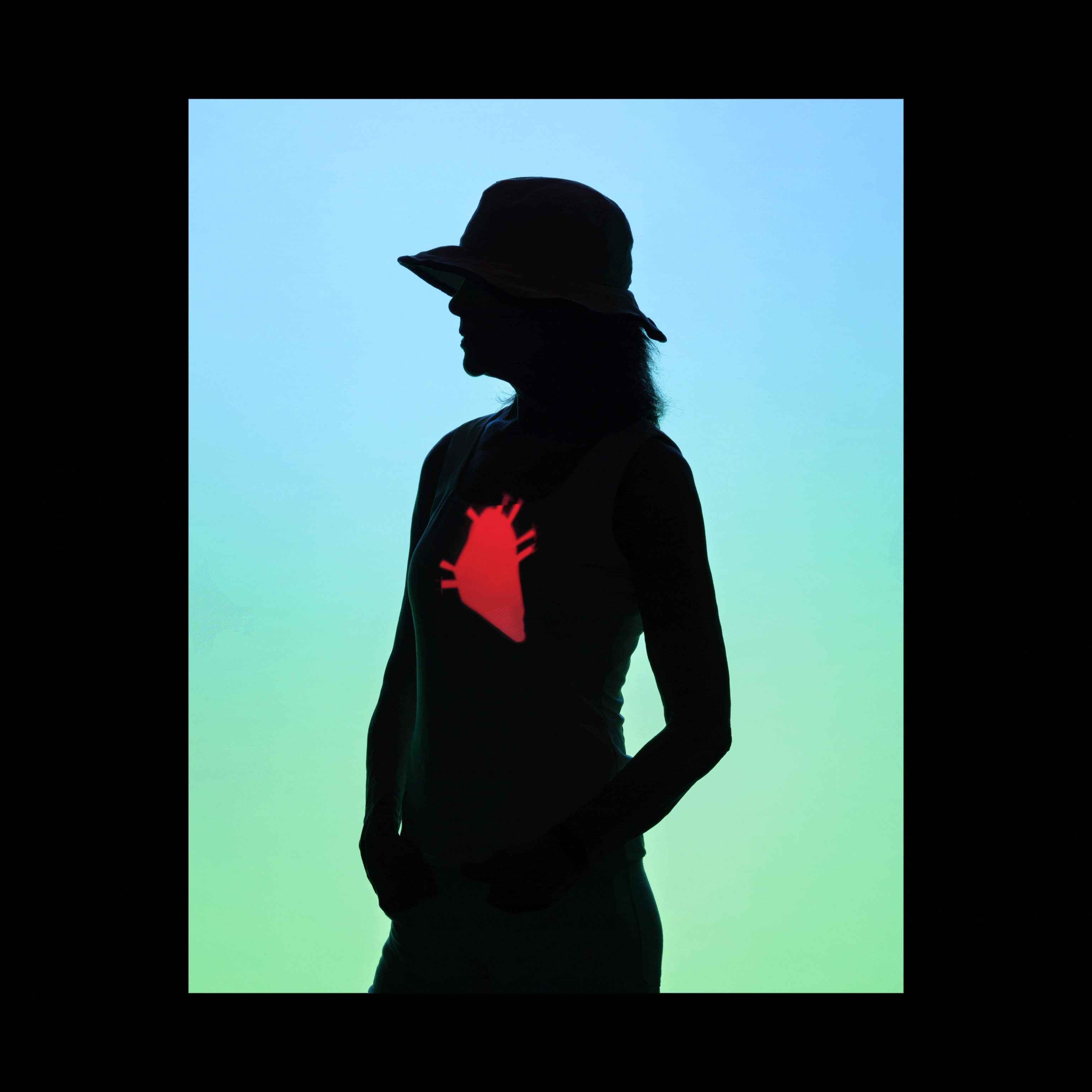 A woman silhouetted against a background that fade from light blue to light green; projections of a heart, brain, and humerus bone cycle every second, appearing on the silhouetted woman's body