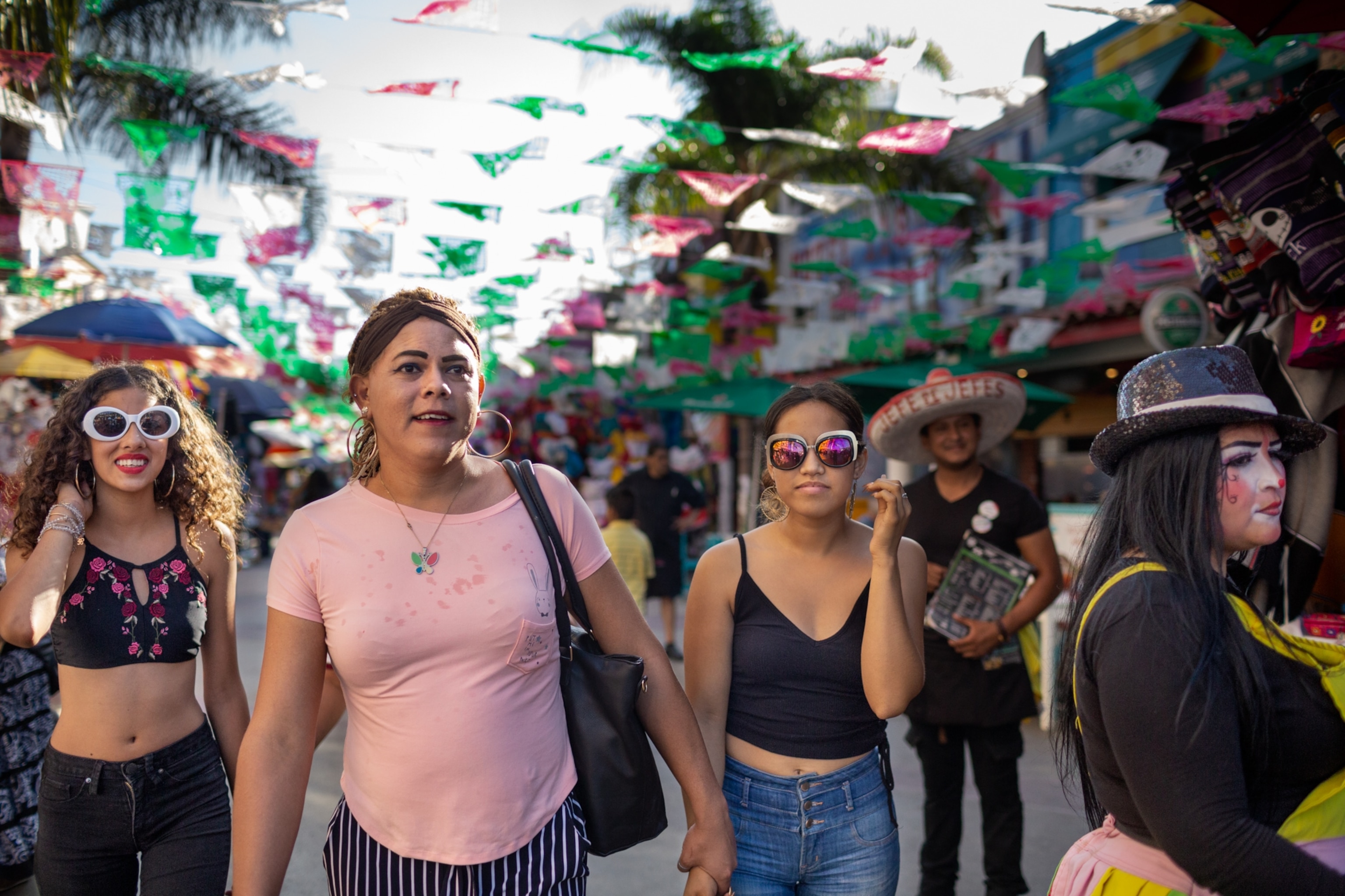 three woman walking down a busy street under red, white and green flags