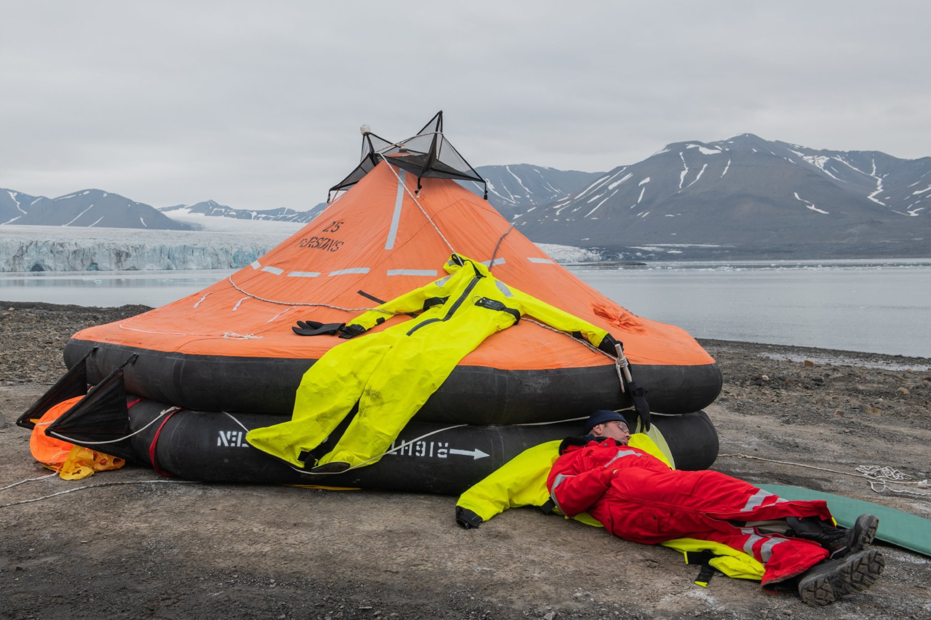 a man sleeping next to a liferaft during survival training