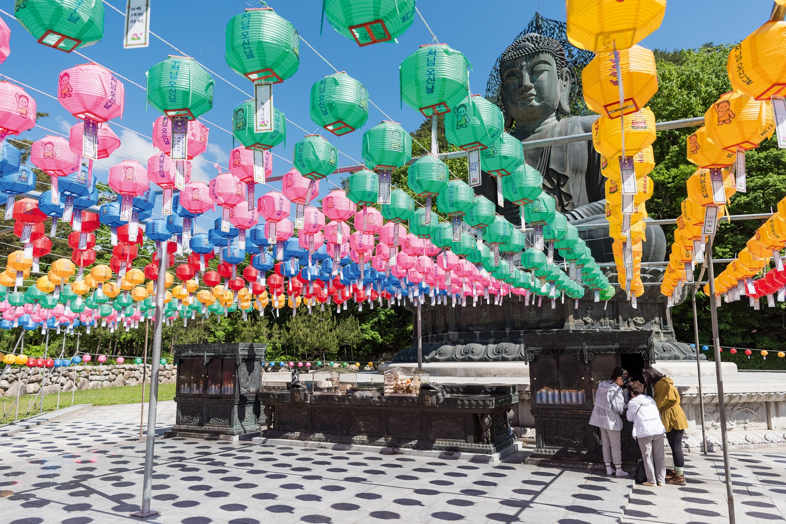 Large Buddha statue with lanterns of different colours strung below