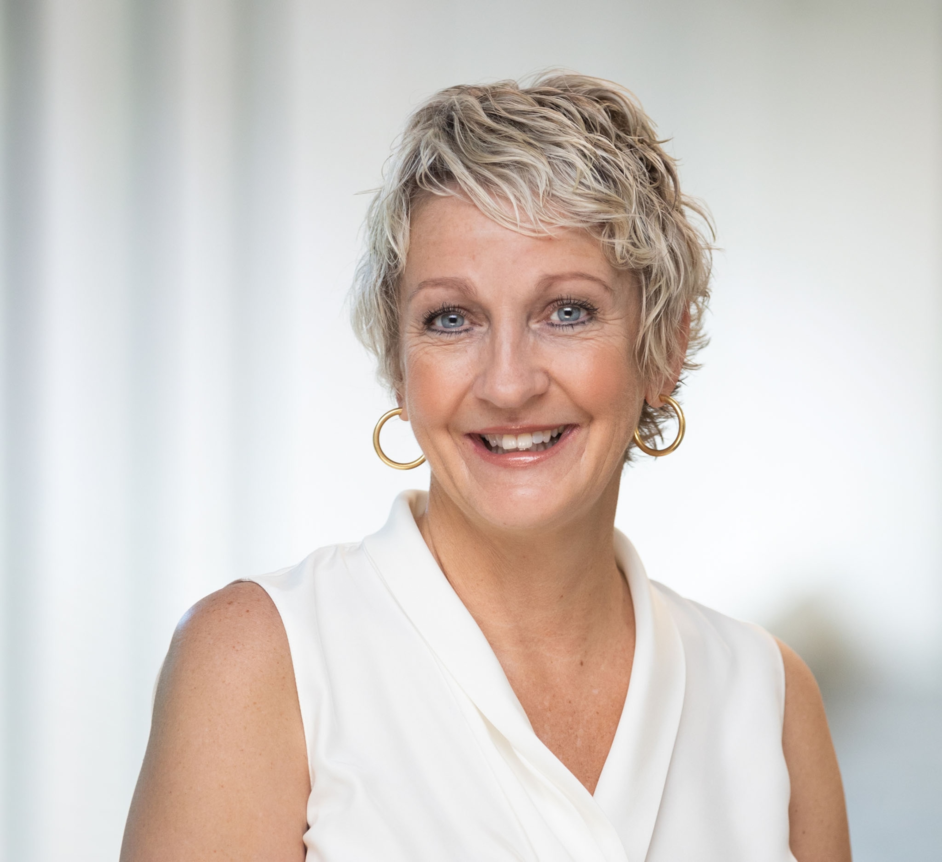 a woman with short blond hair in white blouse.