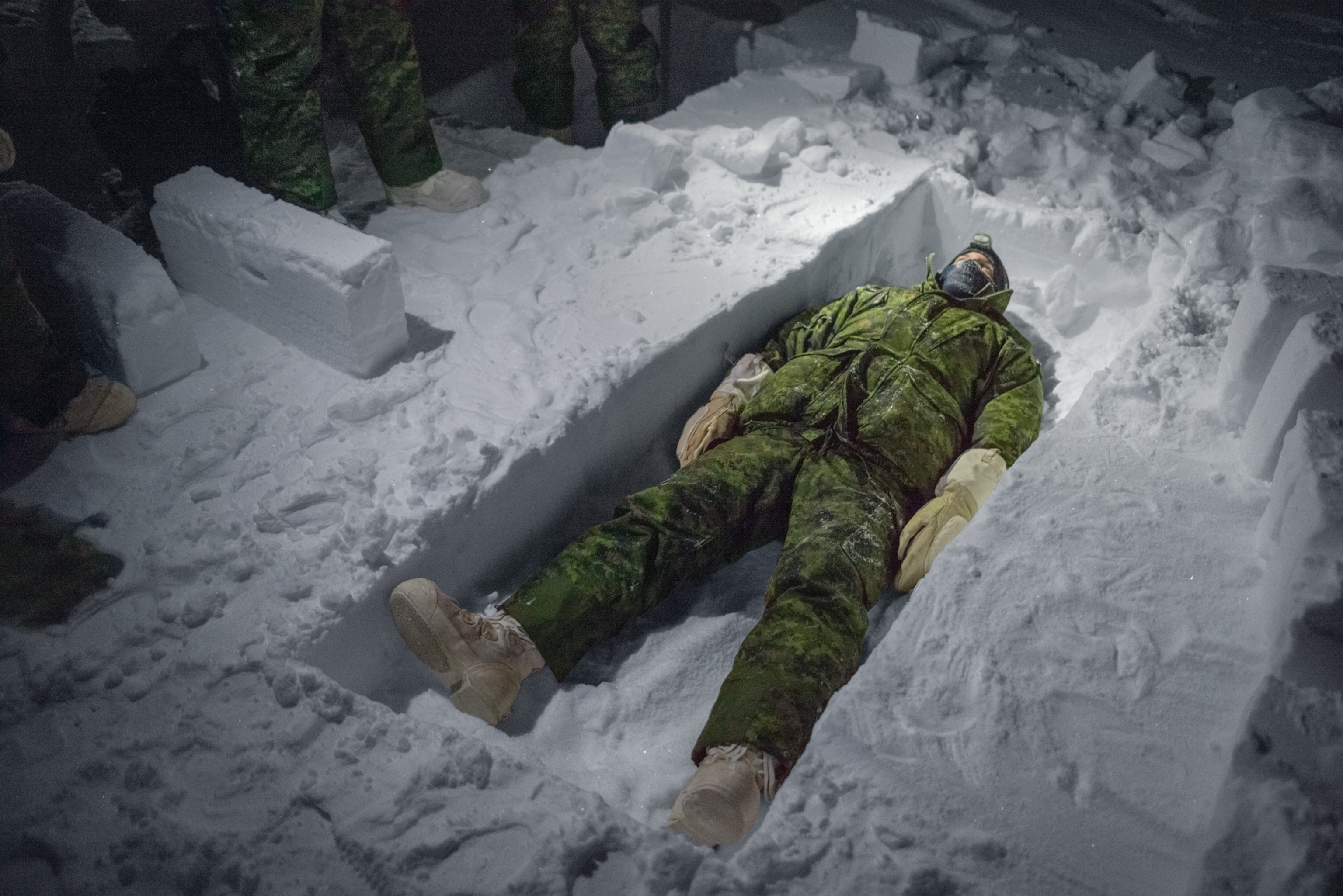 soldier lying in trench cut out in ice.