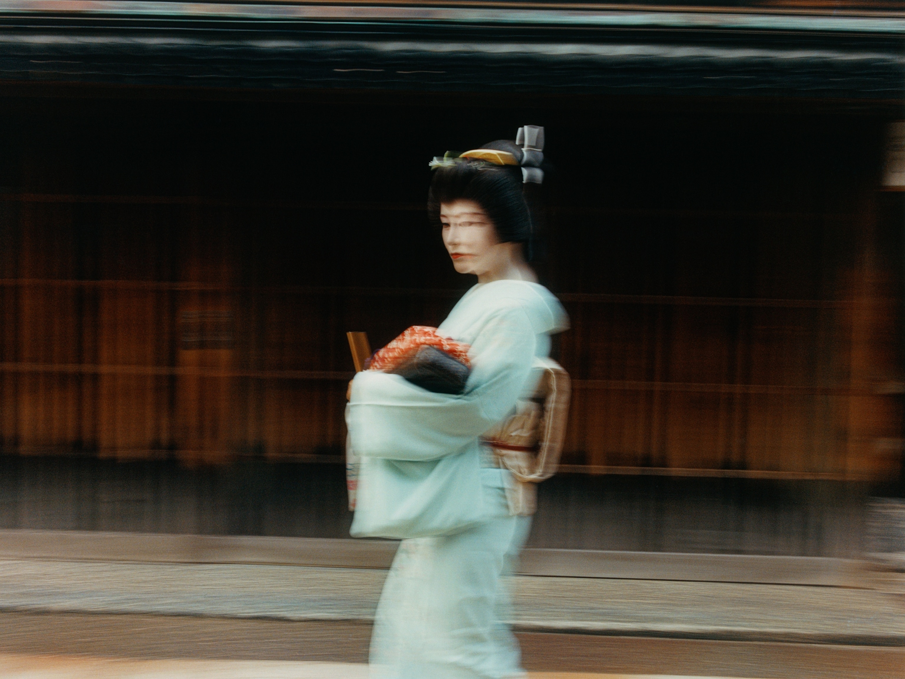 Mikou walking briskly toward a taxi to perform in the Higashi Chaya District.