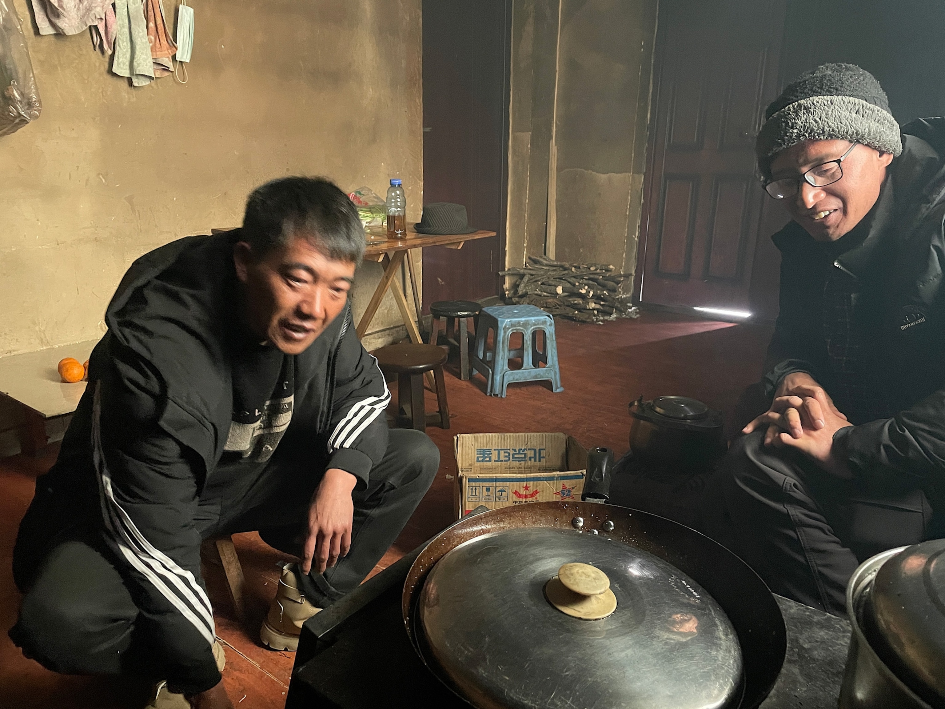 photo of two men seated in front of large pot