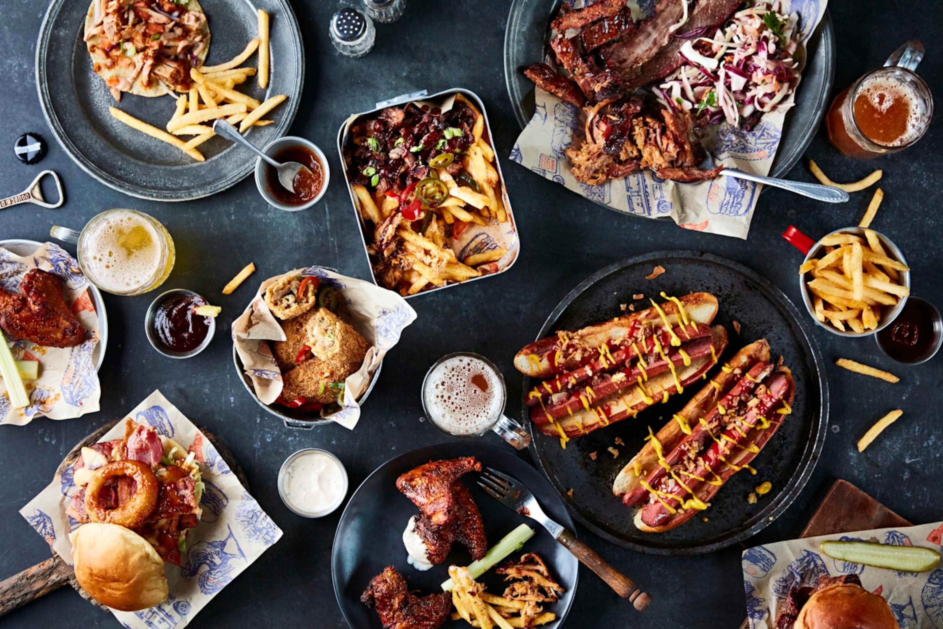 A table full of barbecue food, including burgers and creamed corn.