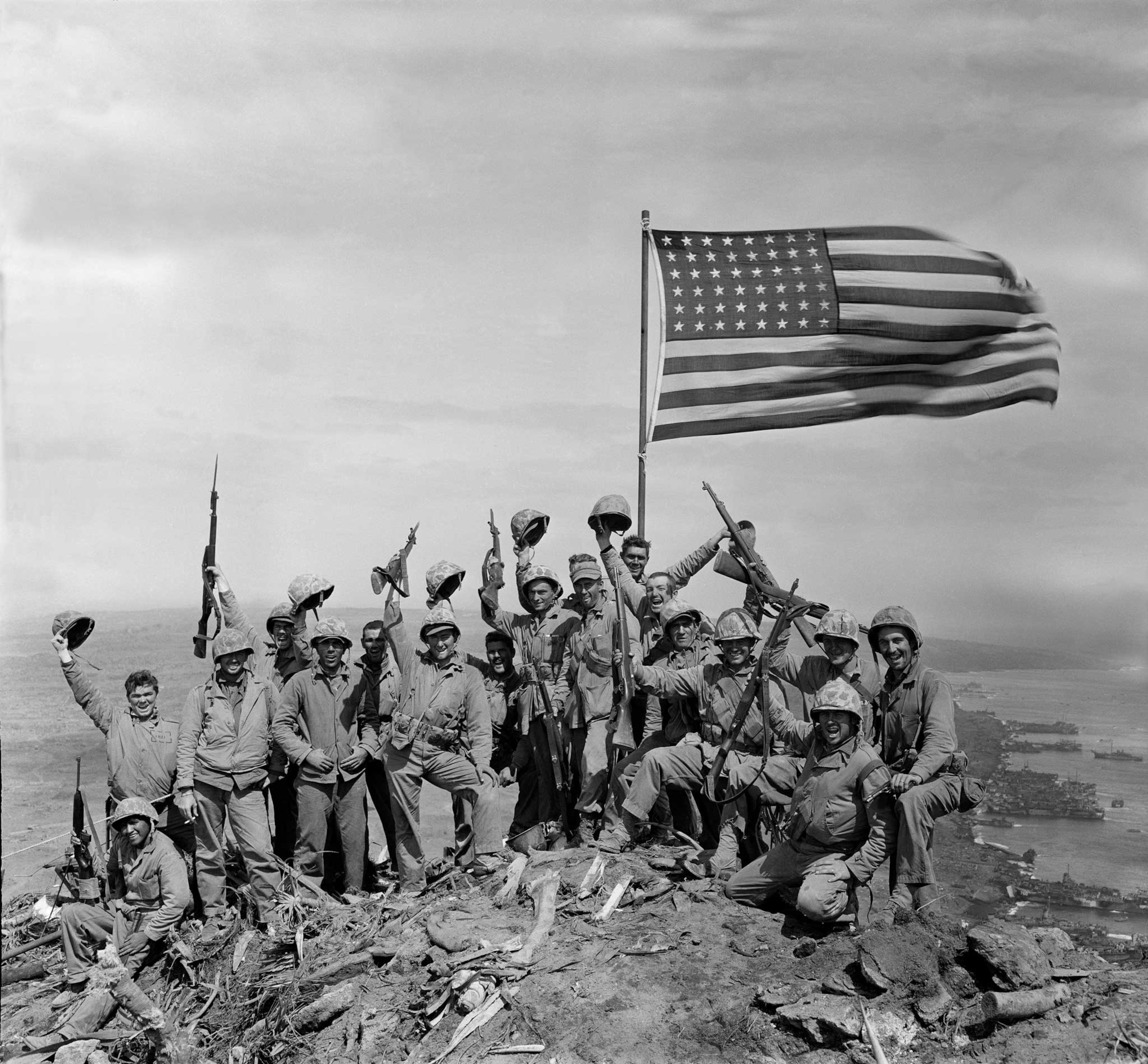 soldiers celebrating on a mountain with the American flag above