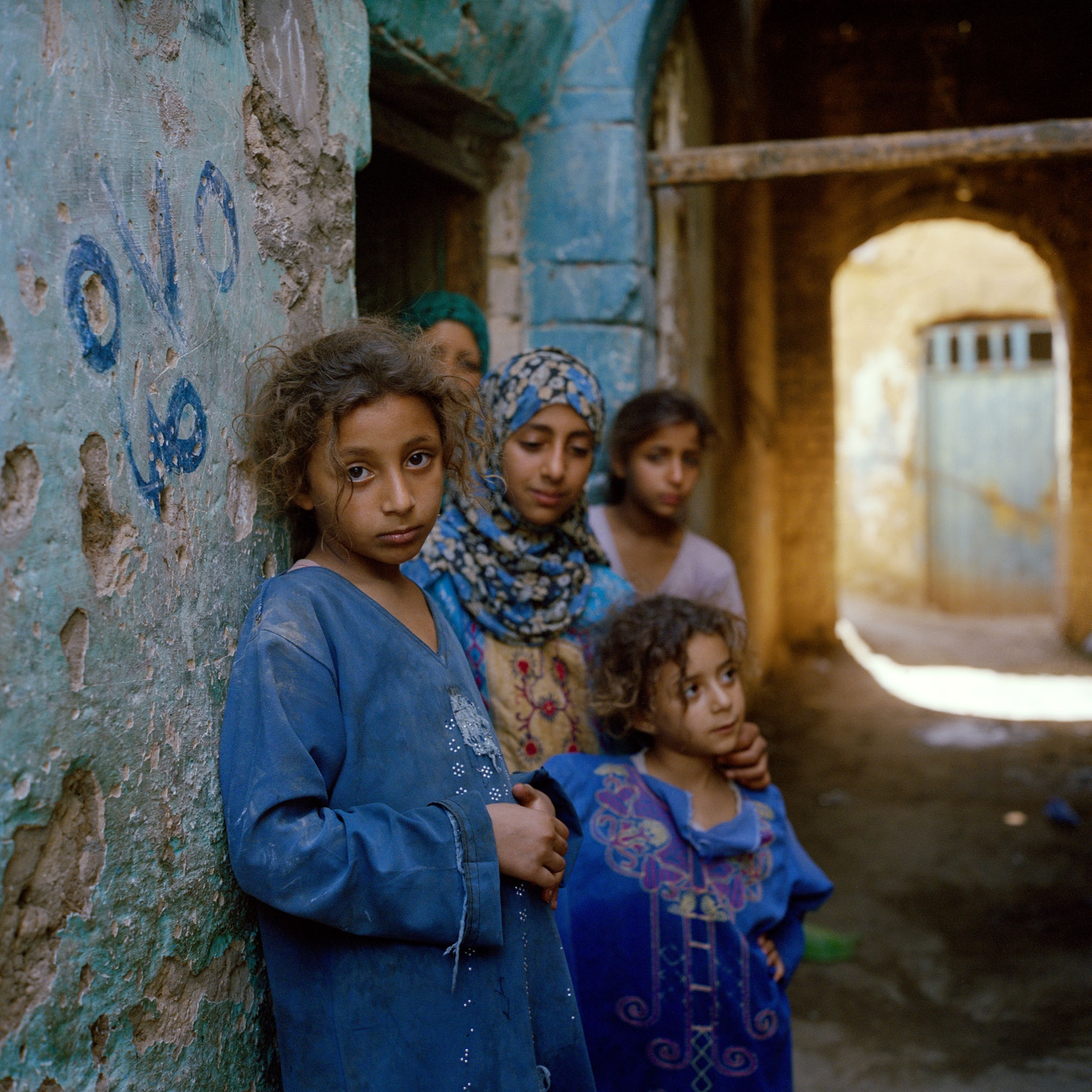 children dressed in blue under the house wall at old city of Minya, Egypt.
