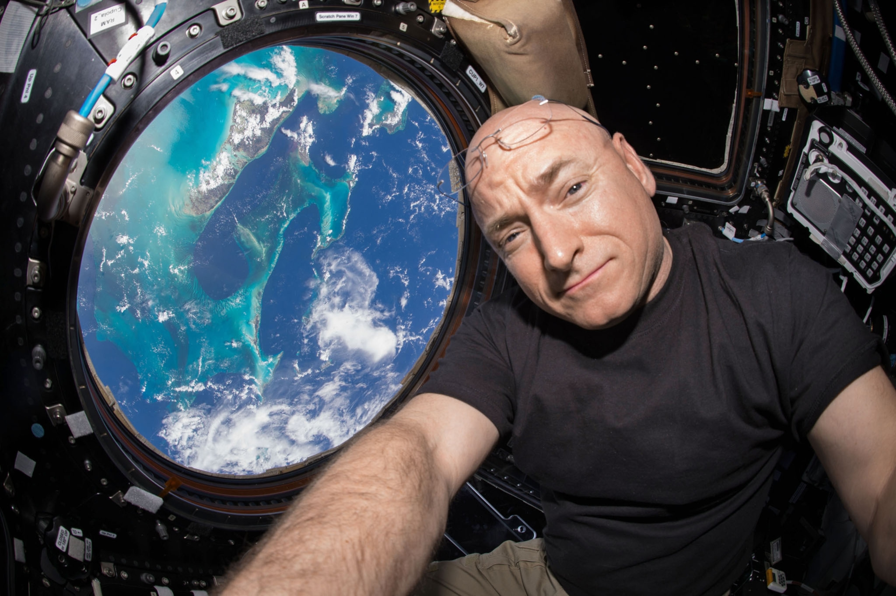 Scott Kelly in space looking out a window with the blue ocean below