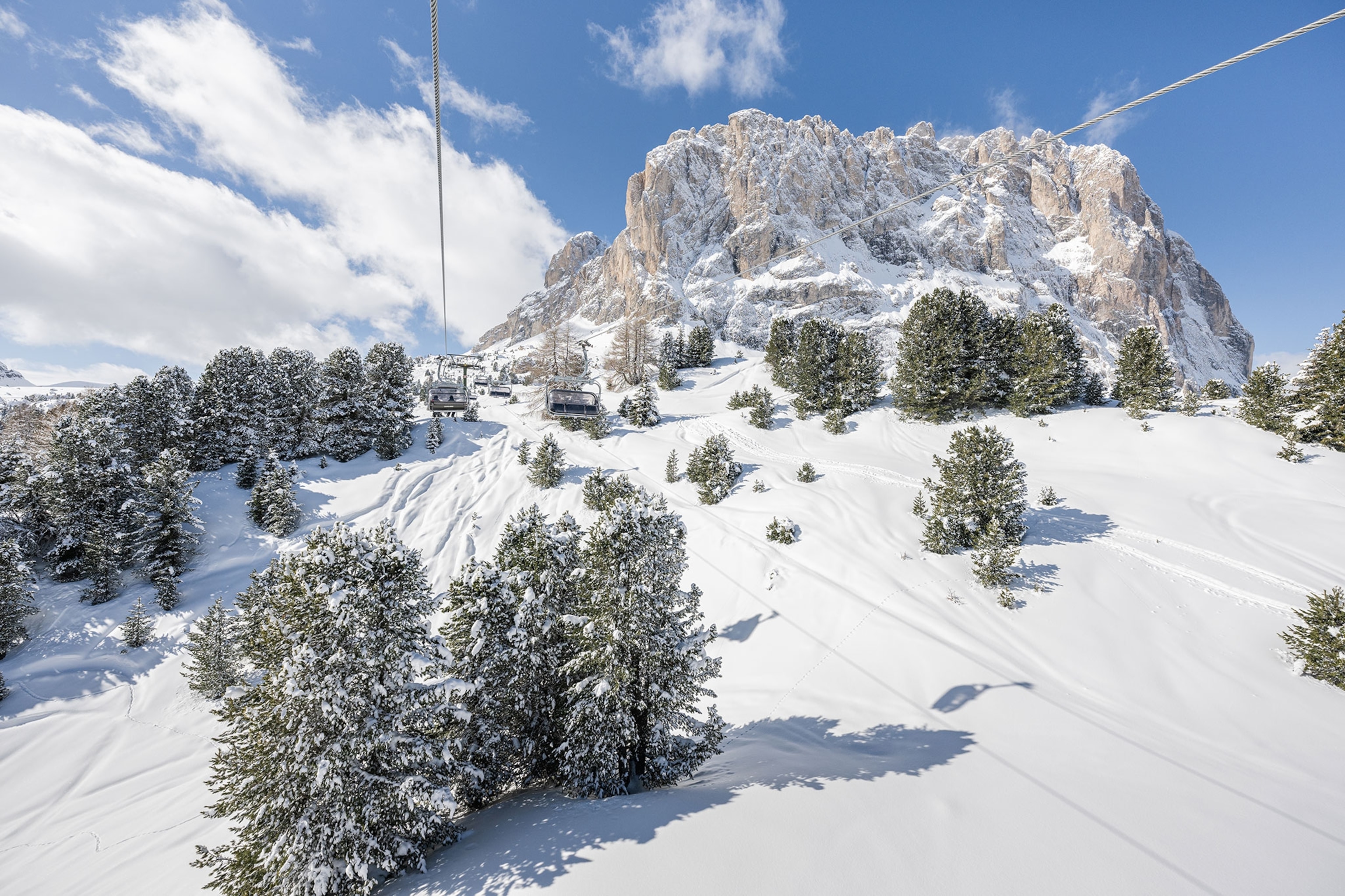 The view of a mountain range in the Dolomites is seen from the viewpoint of a chairlift.