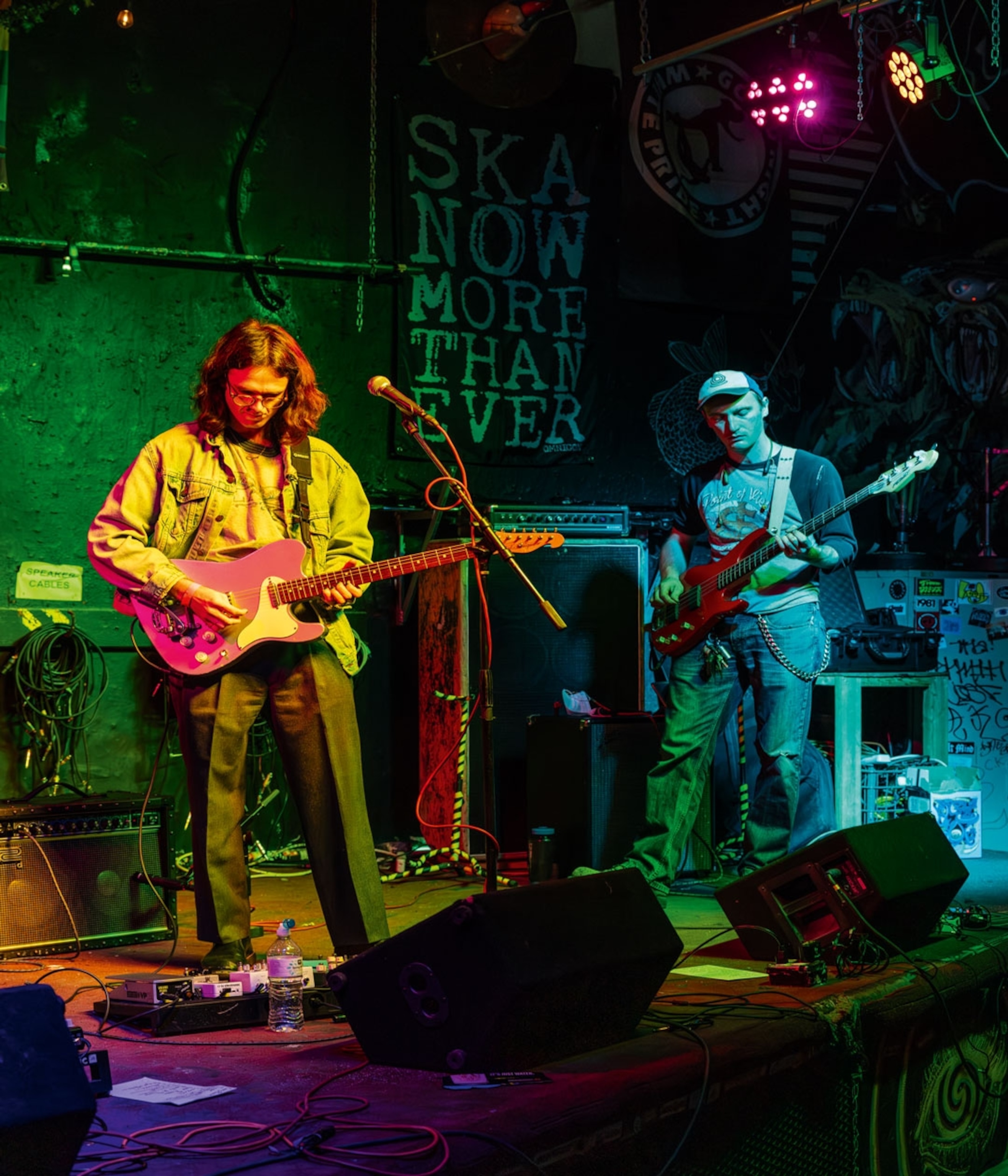 Two men stand on a stage playing guitars.